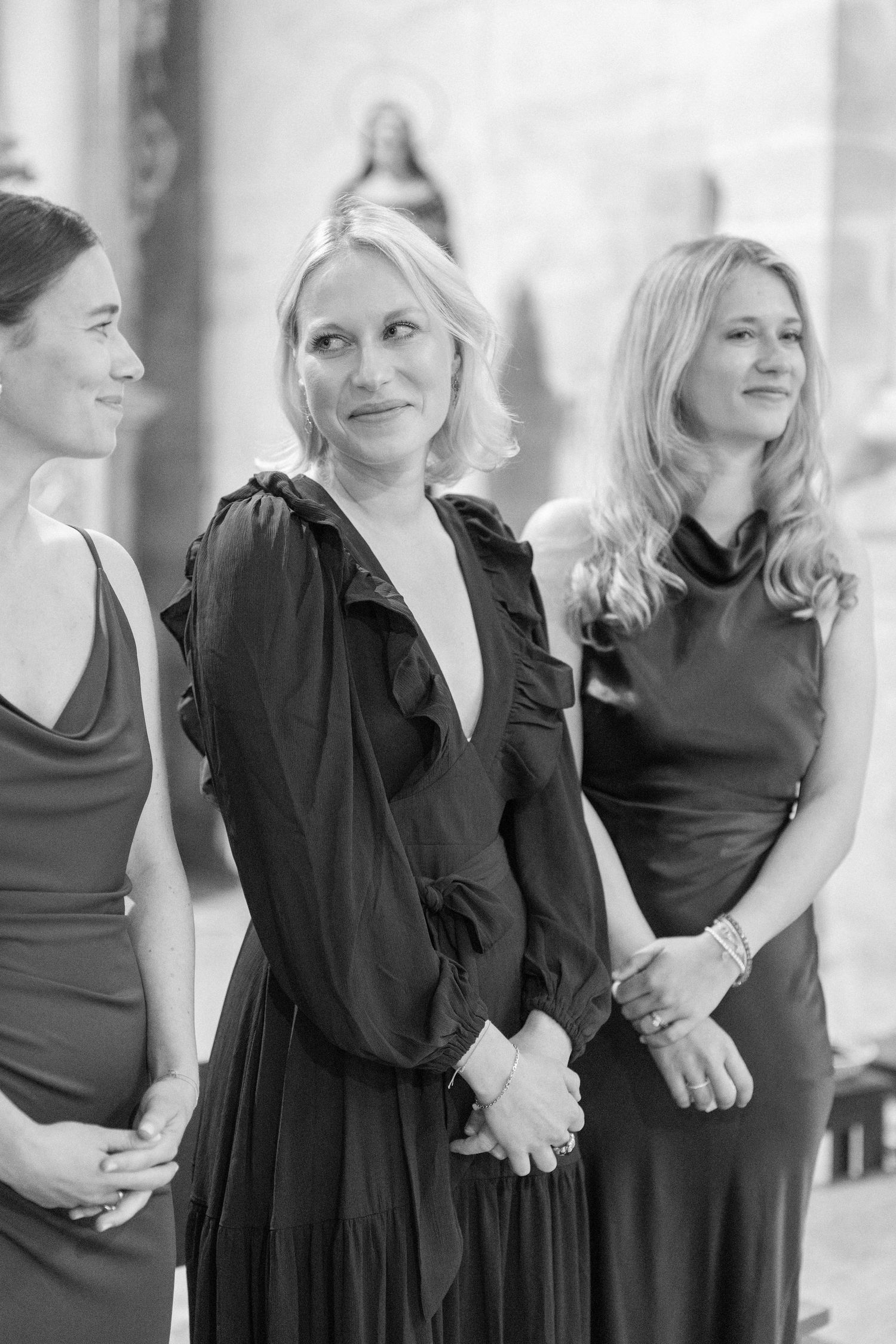 Wedding party members in black dresses gathered together in a candid moment.