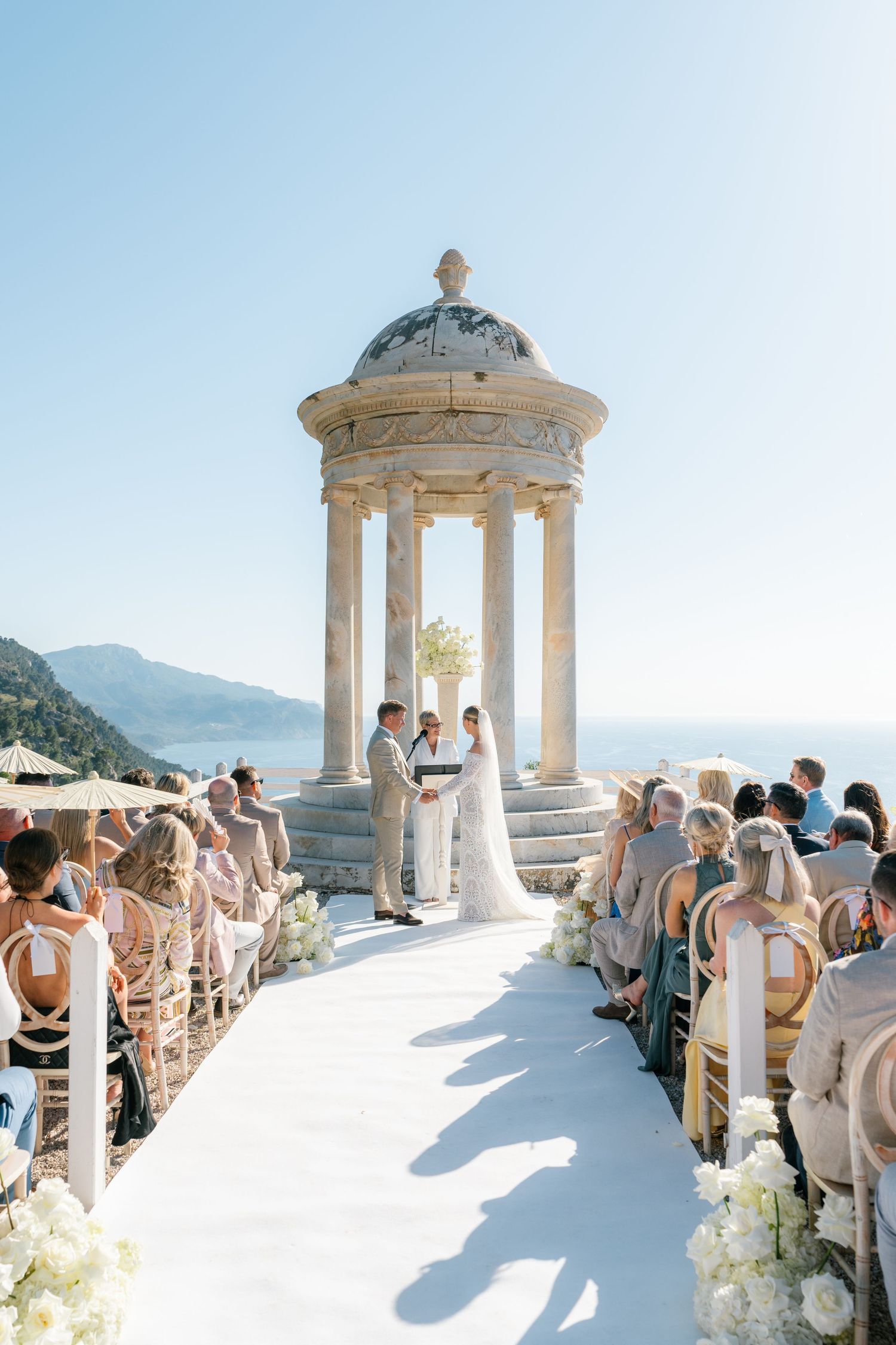 Beautiful outdoor wedding ceremony under white gazebo with mountain backdrop.