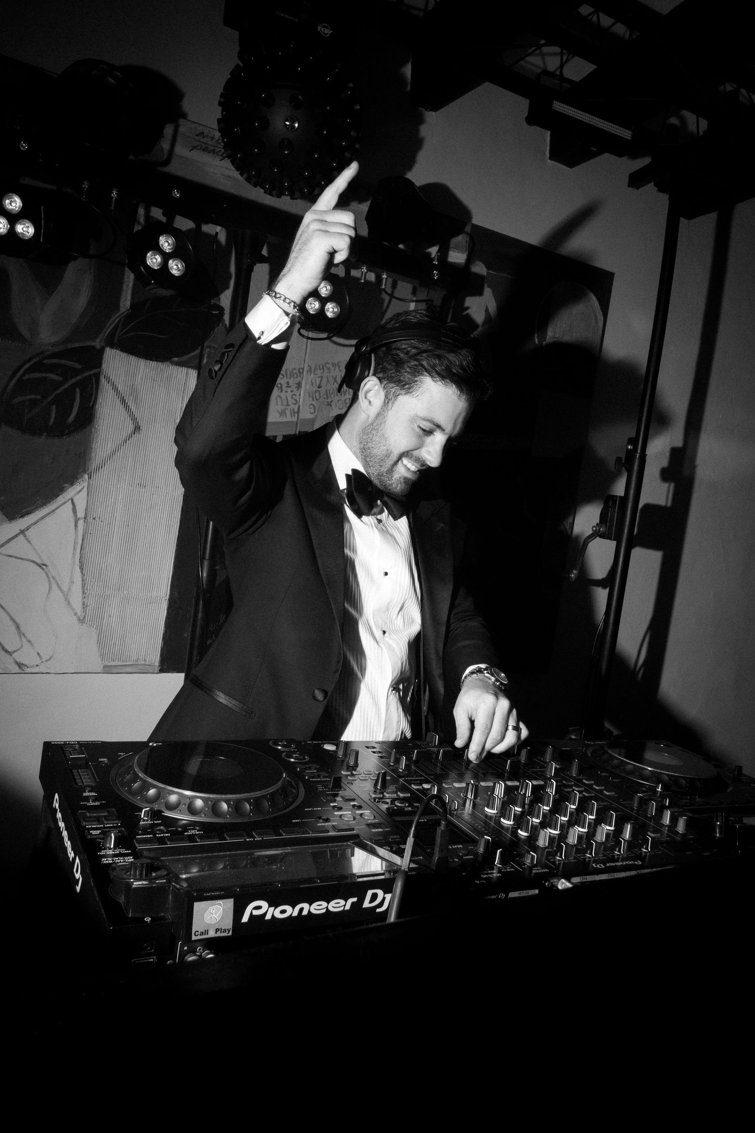DJ performs at event using Pioneer equipment in dramatic black and white lighting.
