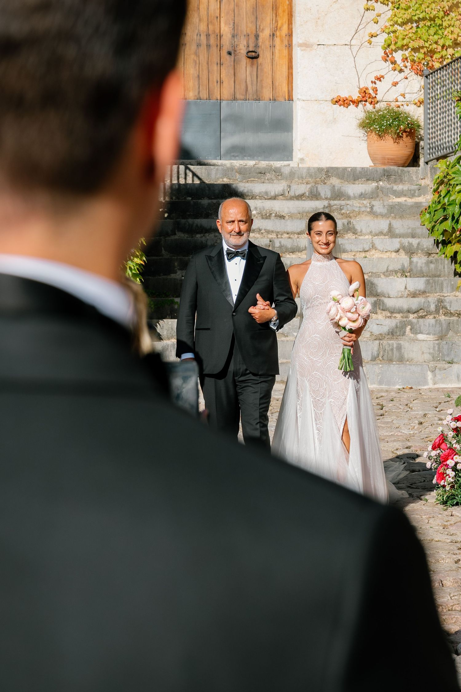 Wedding ceremony processional on stone steps at a Mediterranean-style venue.