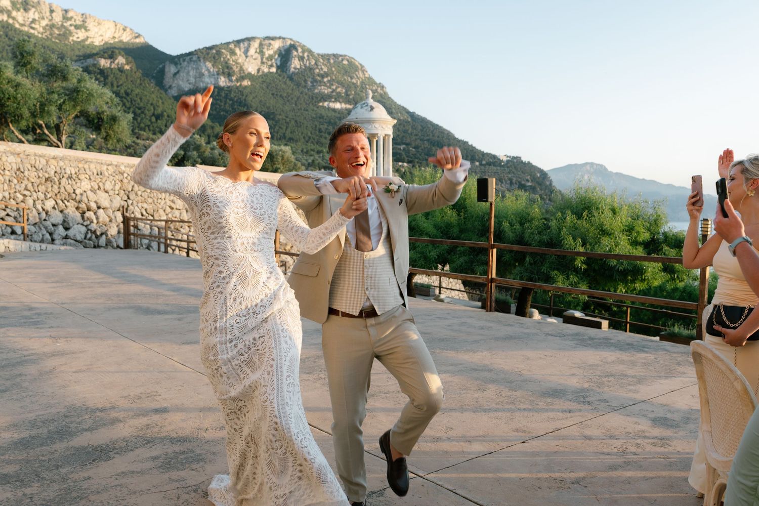 Wedding celebration with mountain backdrop at sunset in outdoor venue.