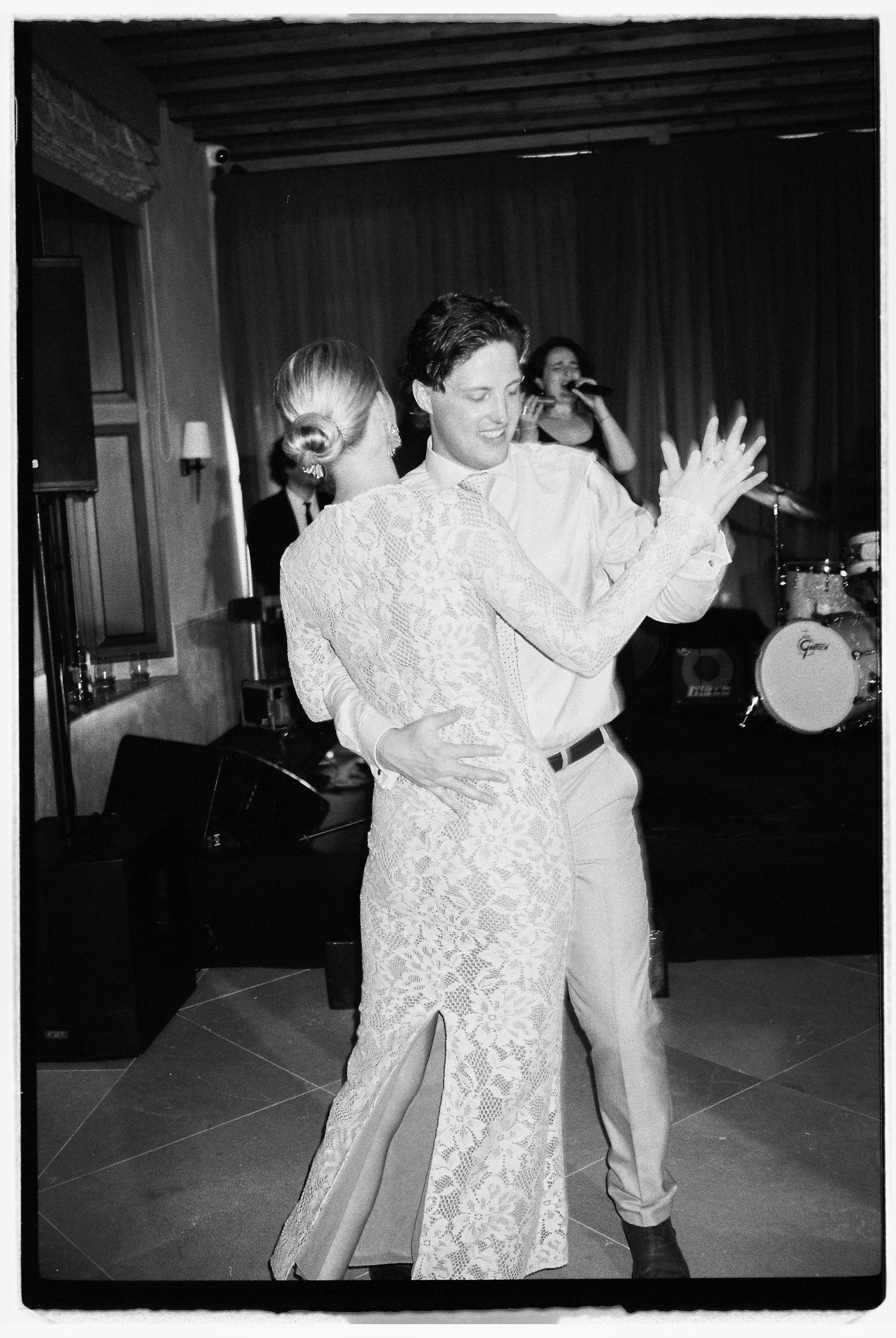Black and white photo of two people dancing at a party with a band in the background.