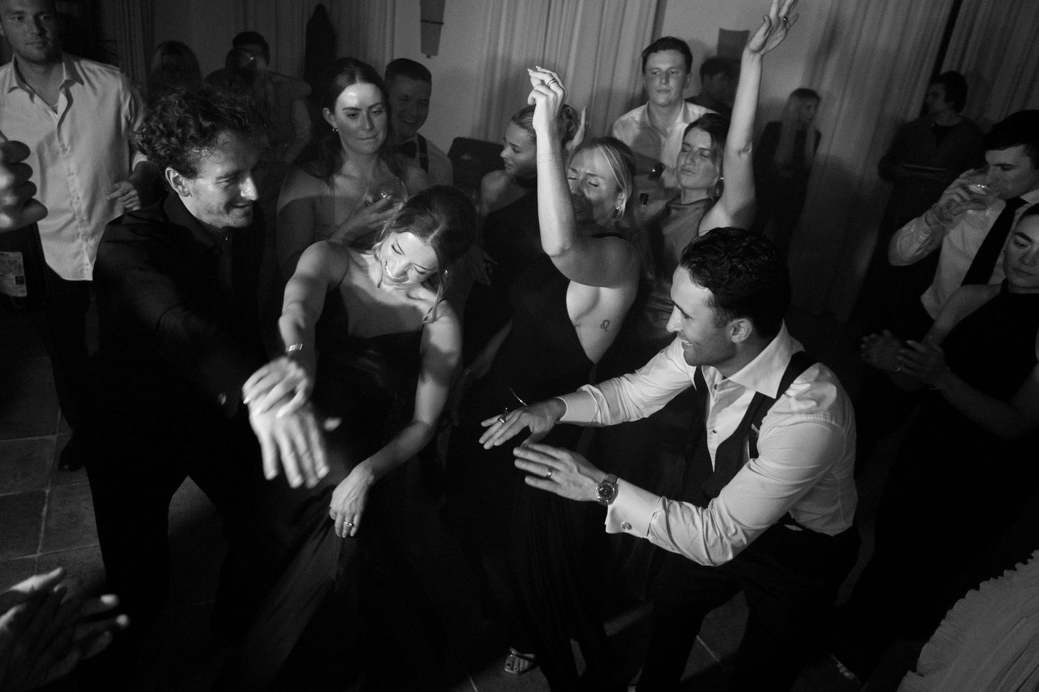 A black and white photograph showing people engaged in an energetic dance party or social gathering.