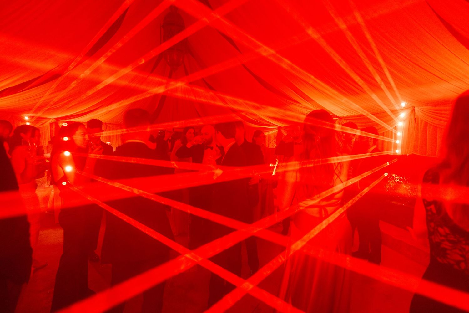 Red laser light show creates dramatic geometric patterns across a dark event space.