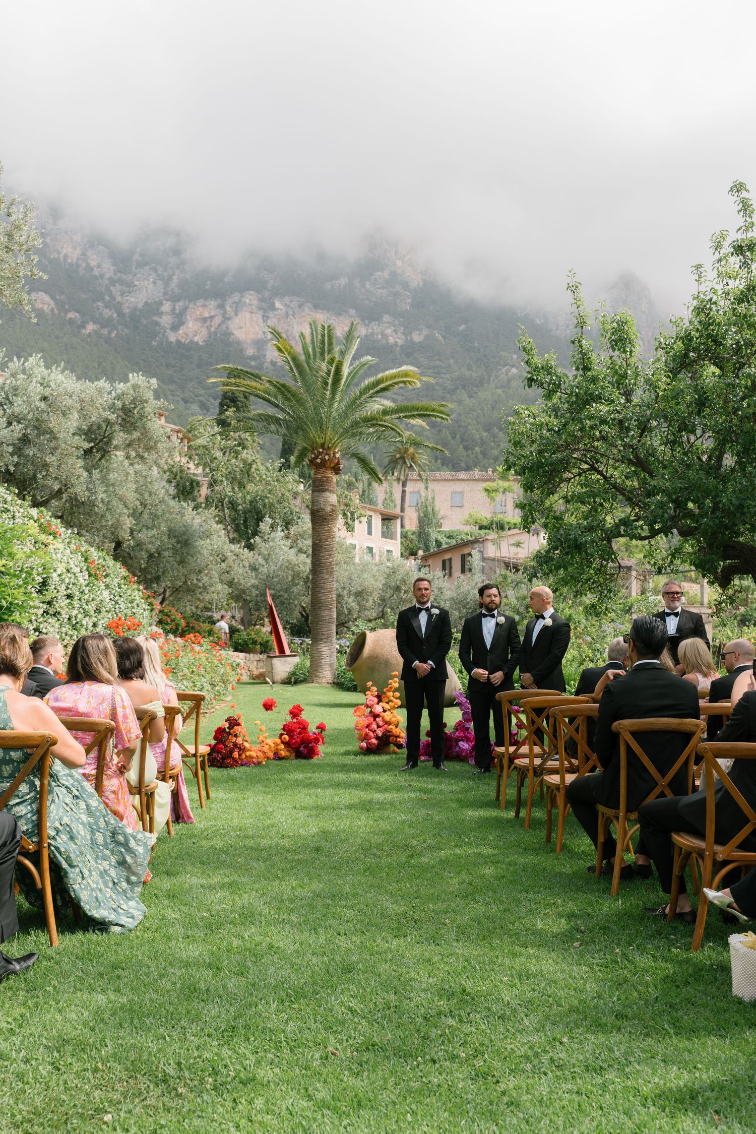 Outdoor garden wedding ceremony setup with wooden chairs and mountain scenery.