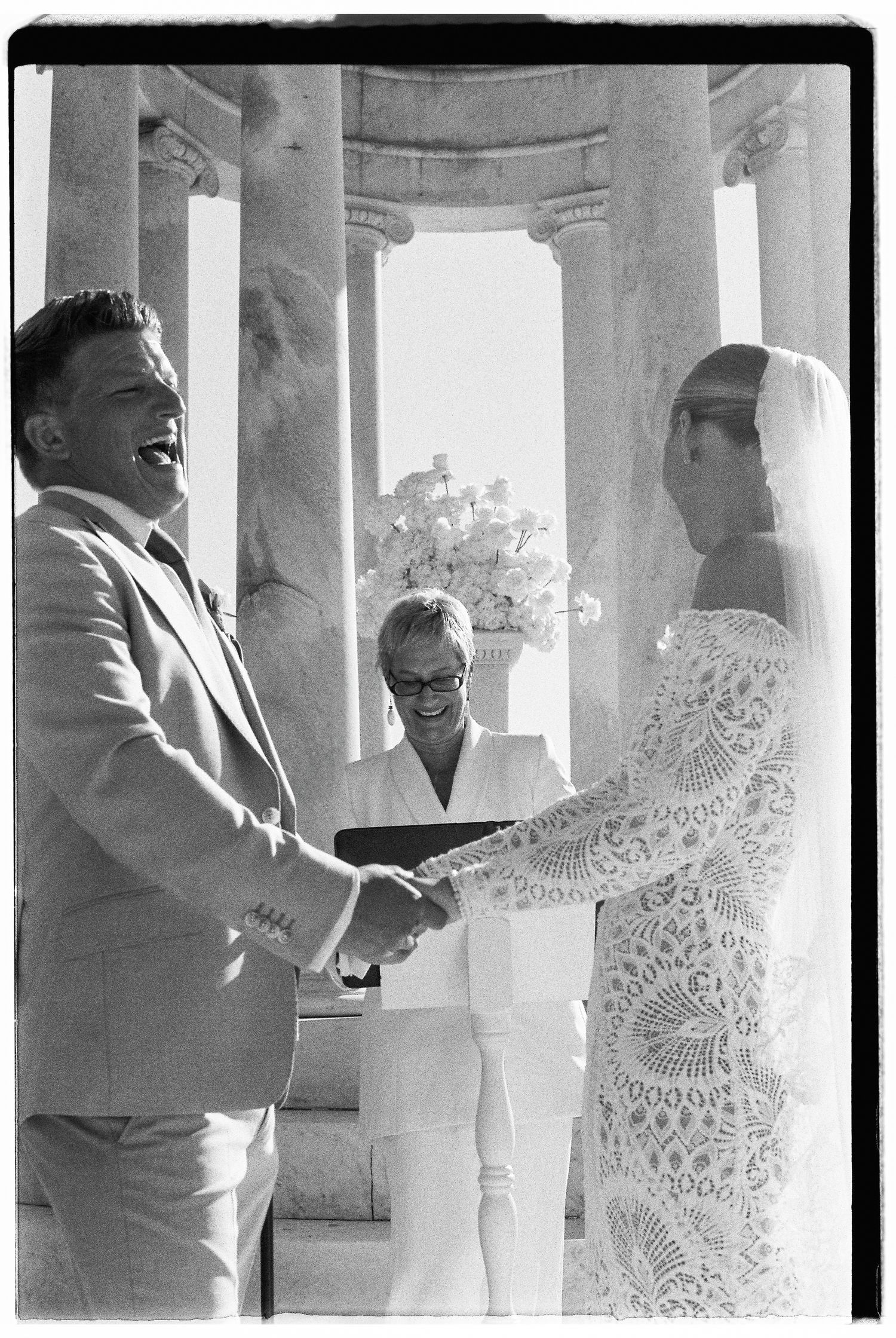 Elegant outdoor ceremony taking place under a columned structure.