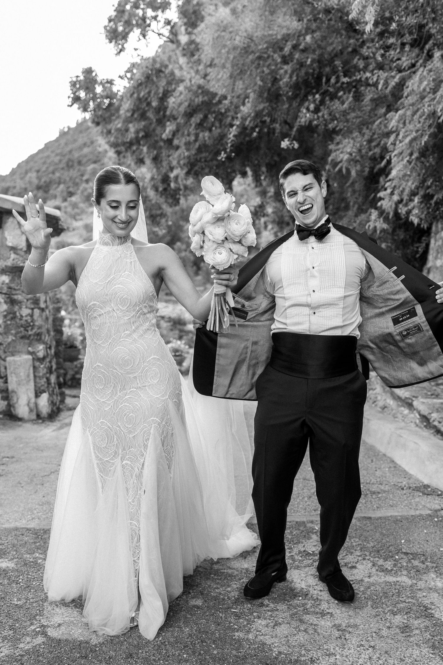 Joyful black and white wedding photo with couple celebrating outdoors.