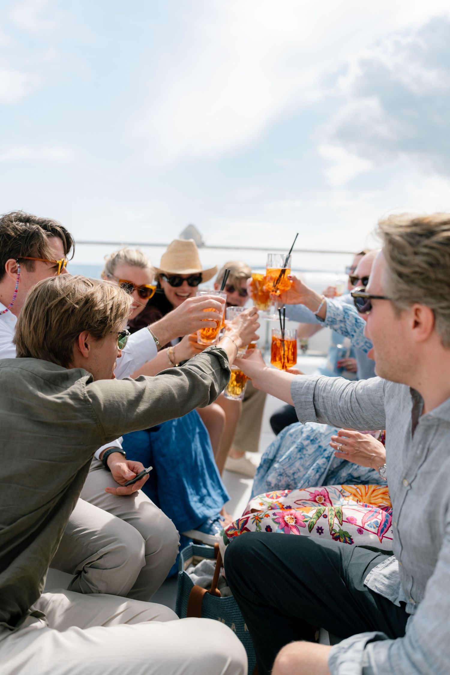 Friends toasting with colorful cocktails during an outdoor celebration on a boat.