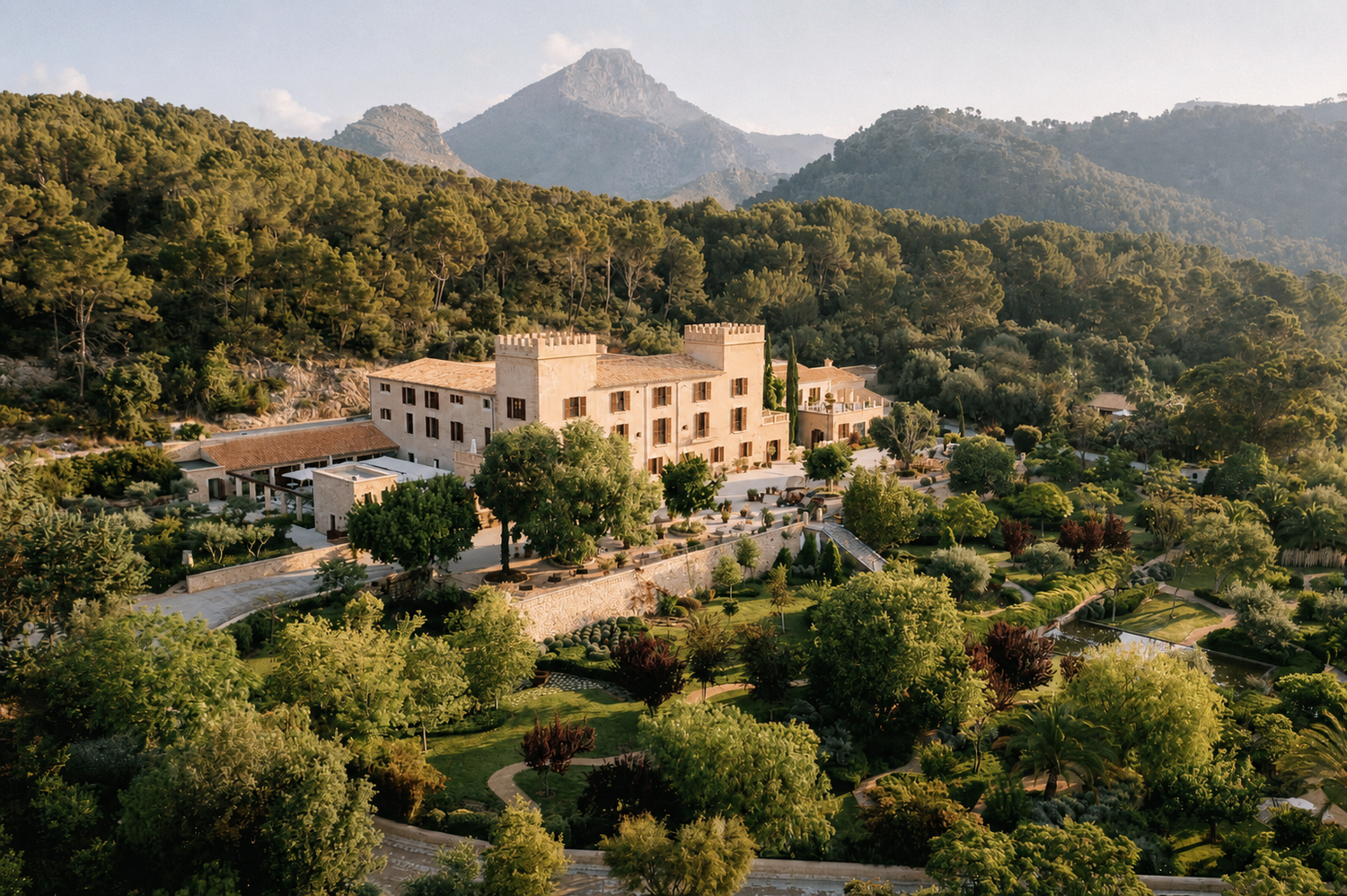 Aerial view of a luxury hotel Castell Son Claret surrounded by lush greenery and mountains in Mallorca, Spain.