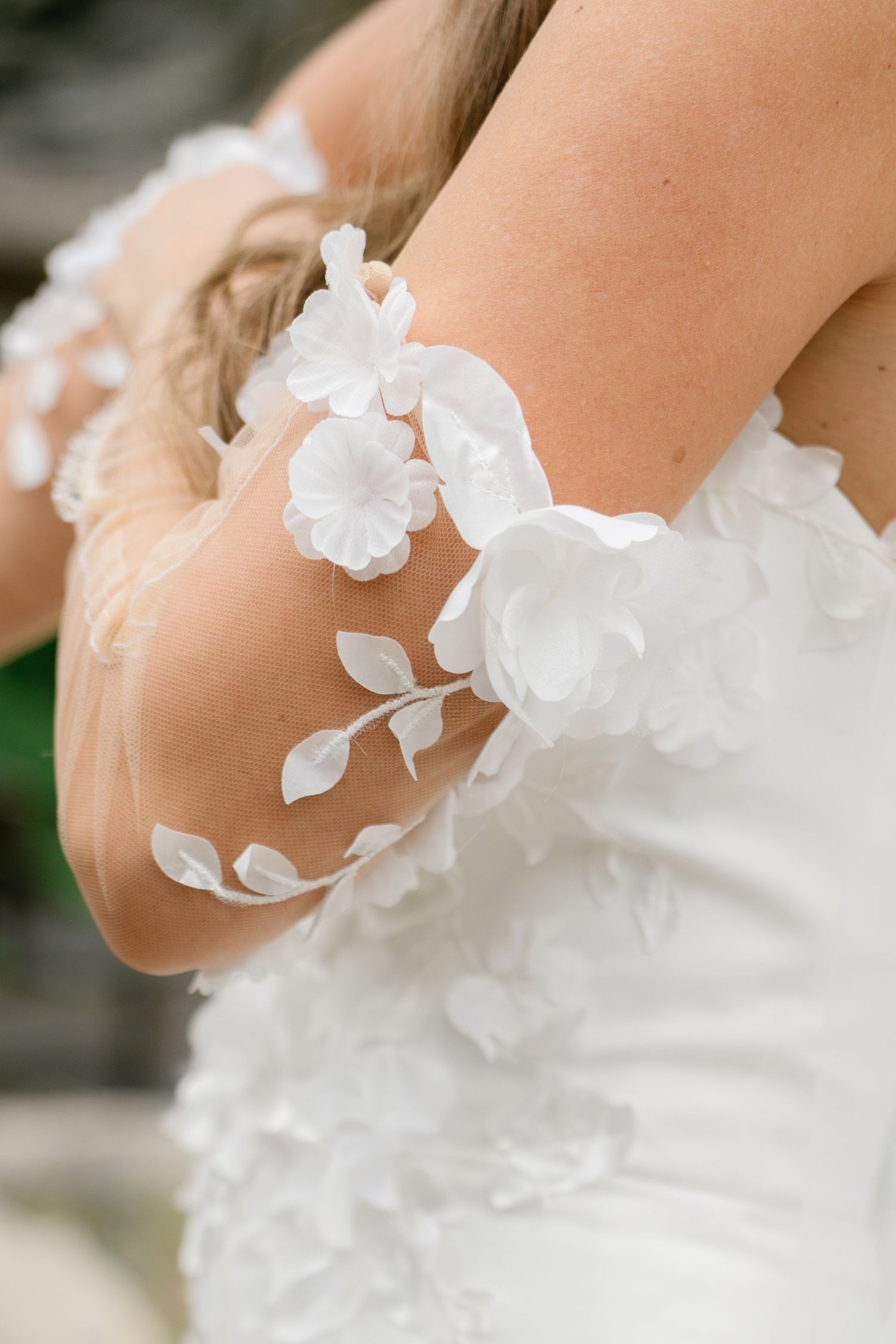 Close-up detail of delicate white floral appliques on a wedding dress.