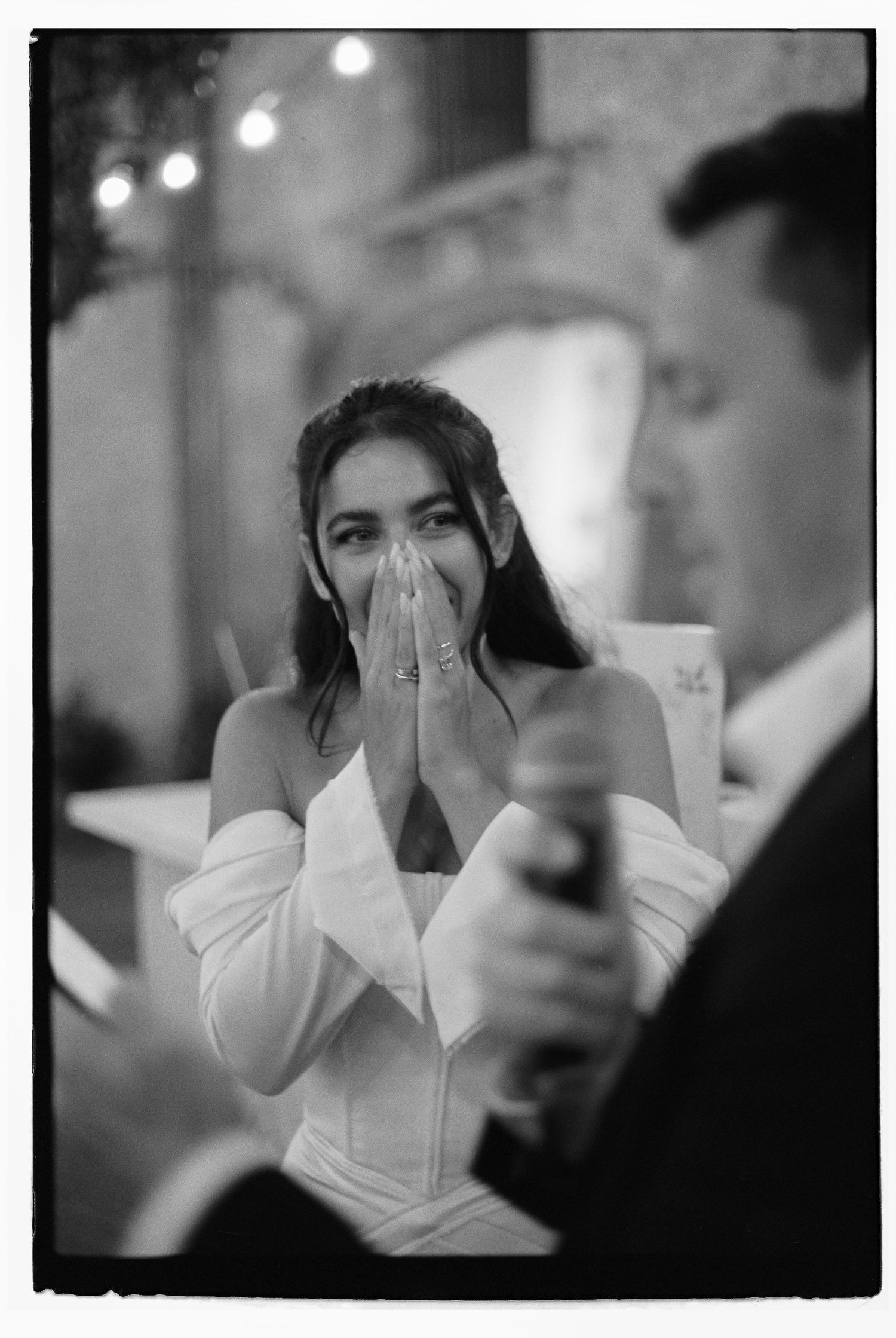 Emotional black and white wedding moment captured under string lights.