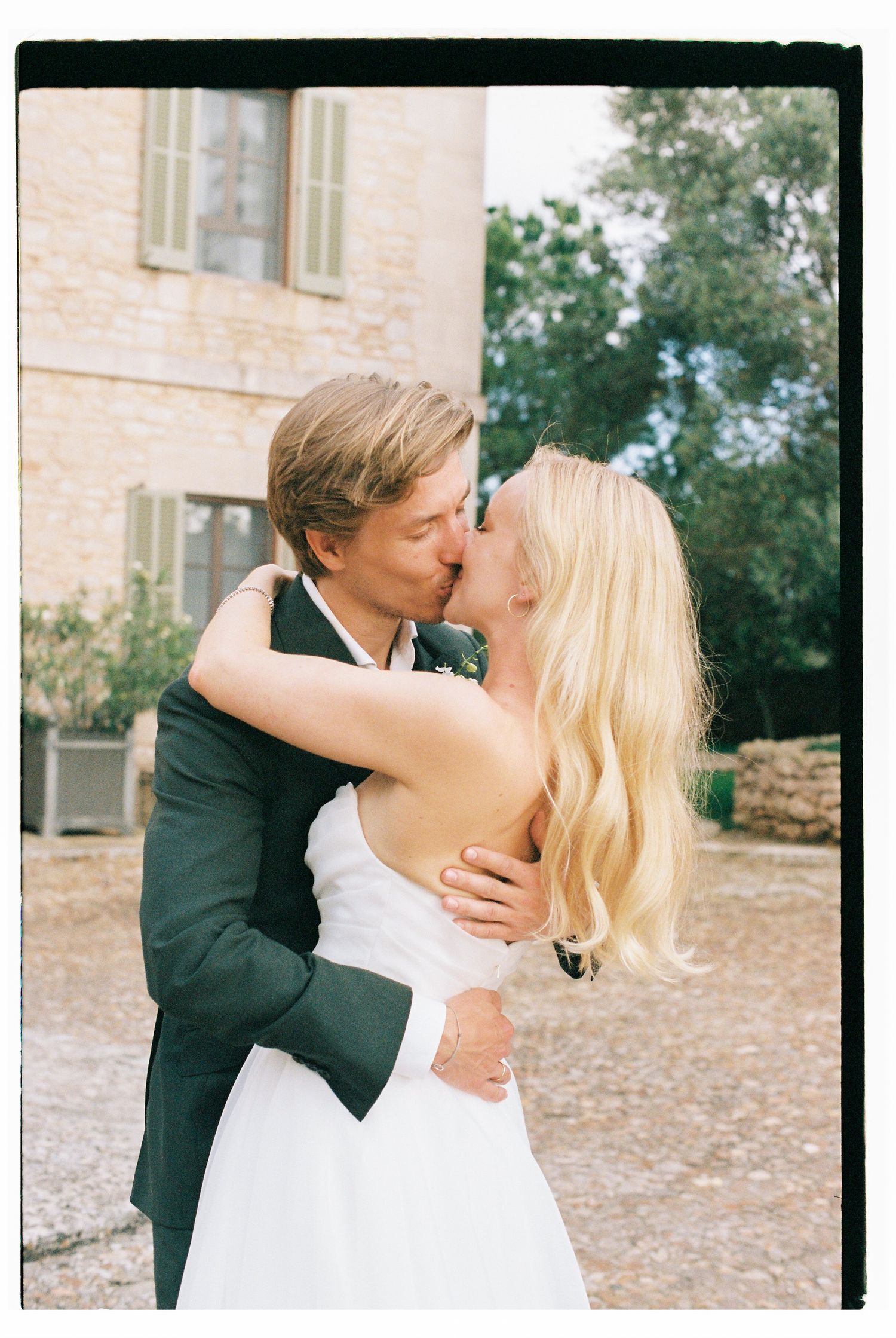 Romantic wedding couple sharing a passionate embrace in an outdoor courtyard.
