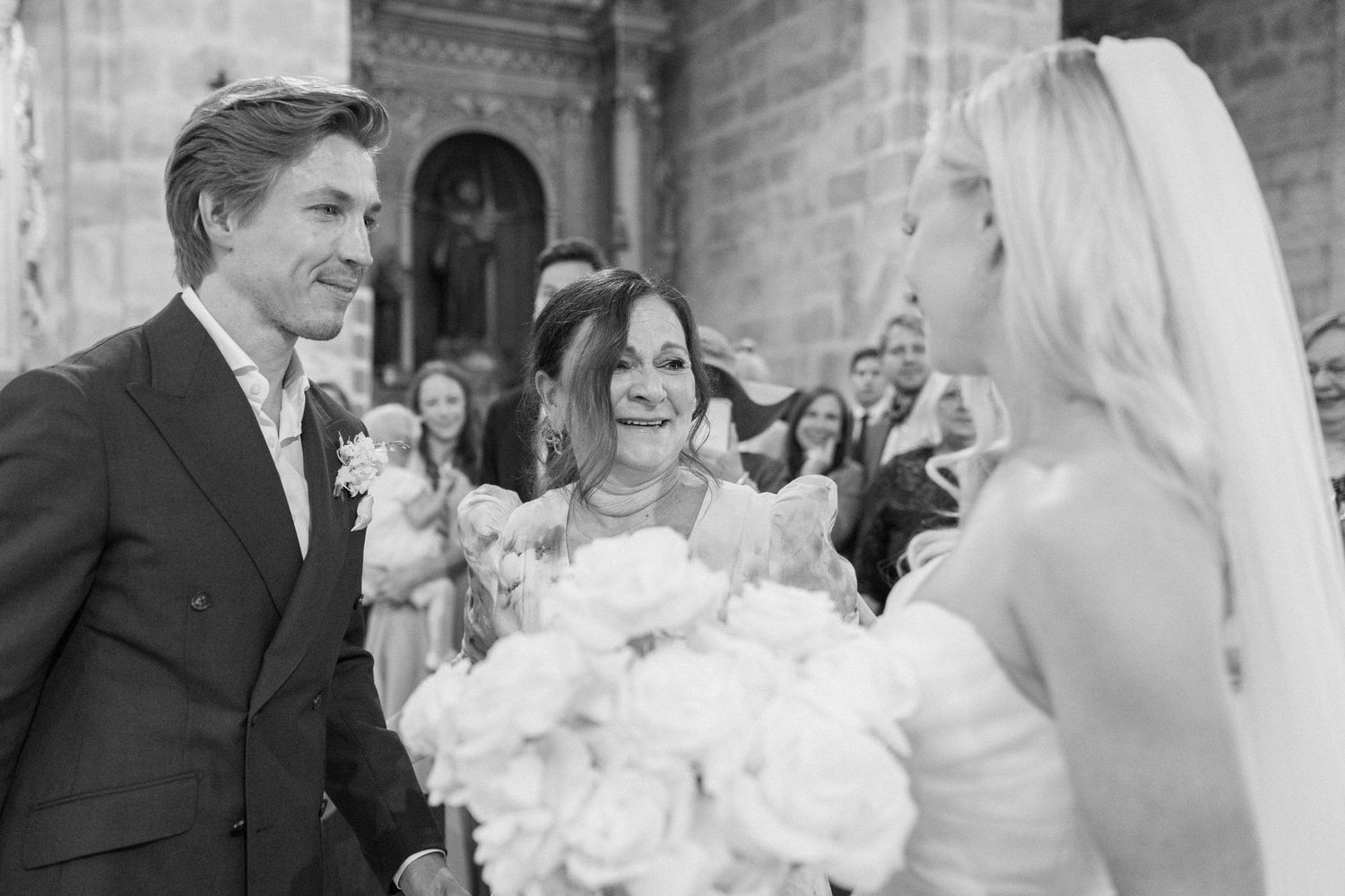 Wedding party celebrating in a historic stone church with elegant floral arrangements.