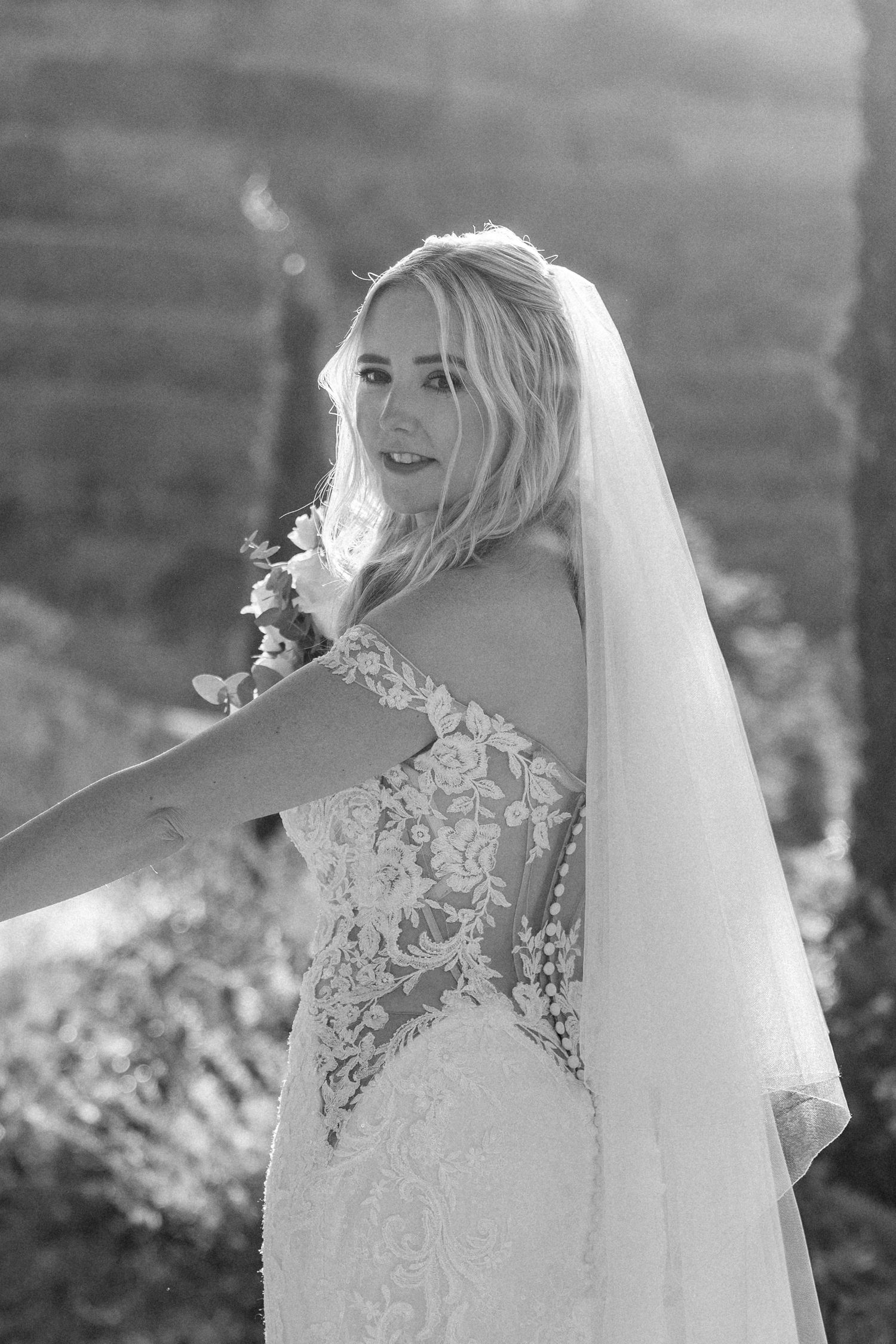 Close-up details of delicate lace wedding dress with flowing veil in natural light.