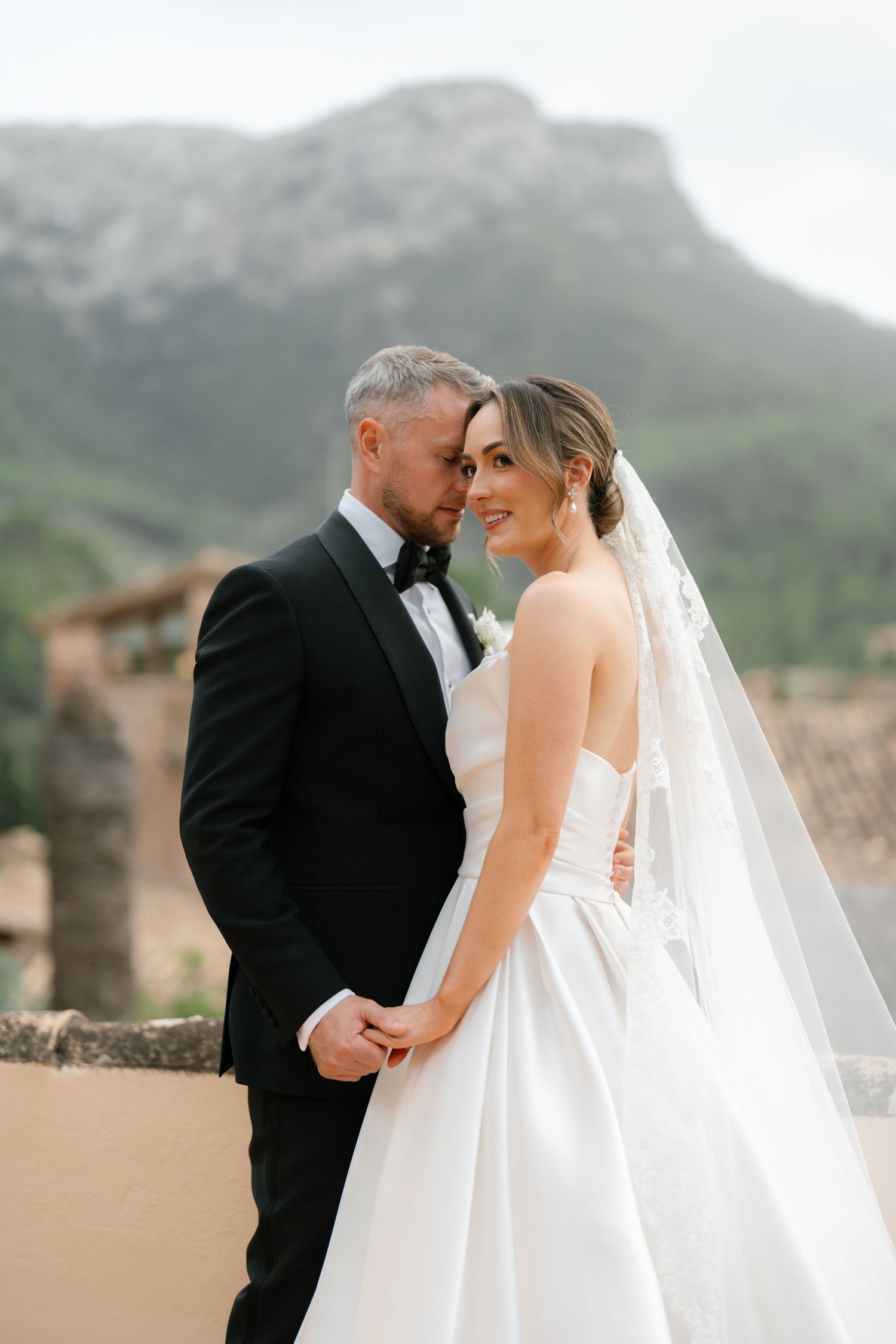 Romantic wedding moment captured against a backdrop of Mediterranean mountains.