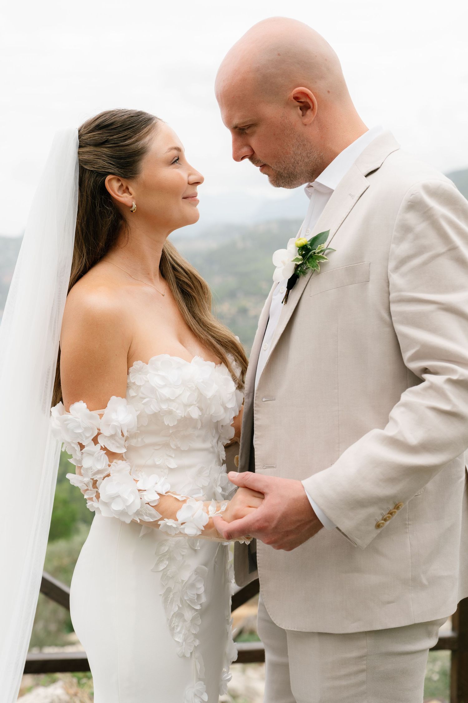 Wedding couple shares candid moments in light-colored attire against a coastal backdrop.