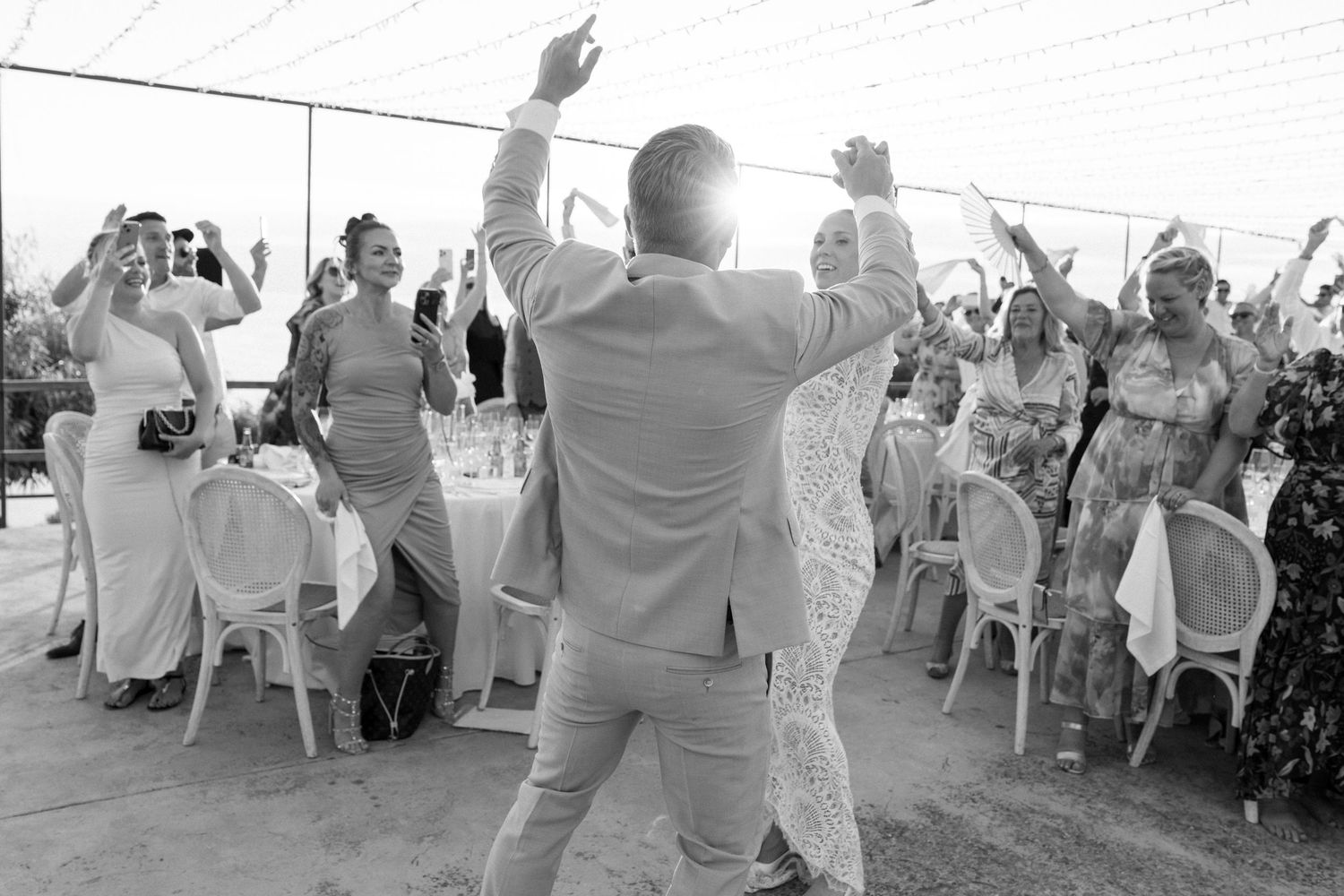 Wedding guests dancing in formal attire at an outdoor reception celebration.