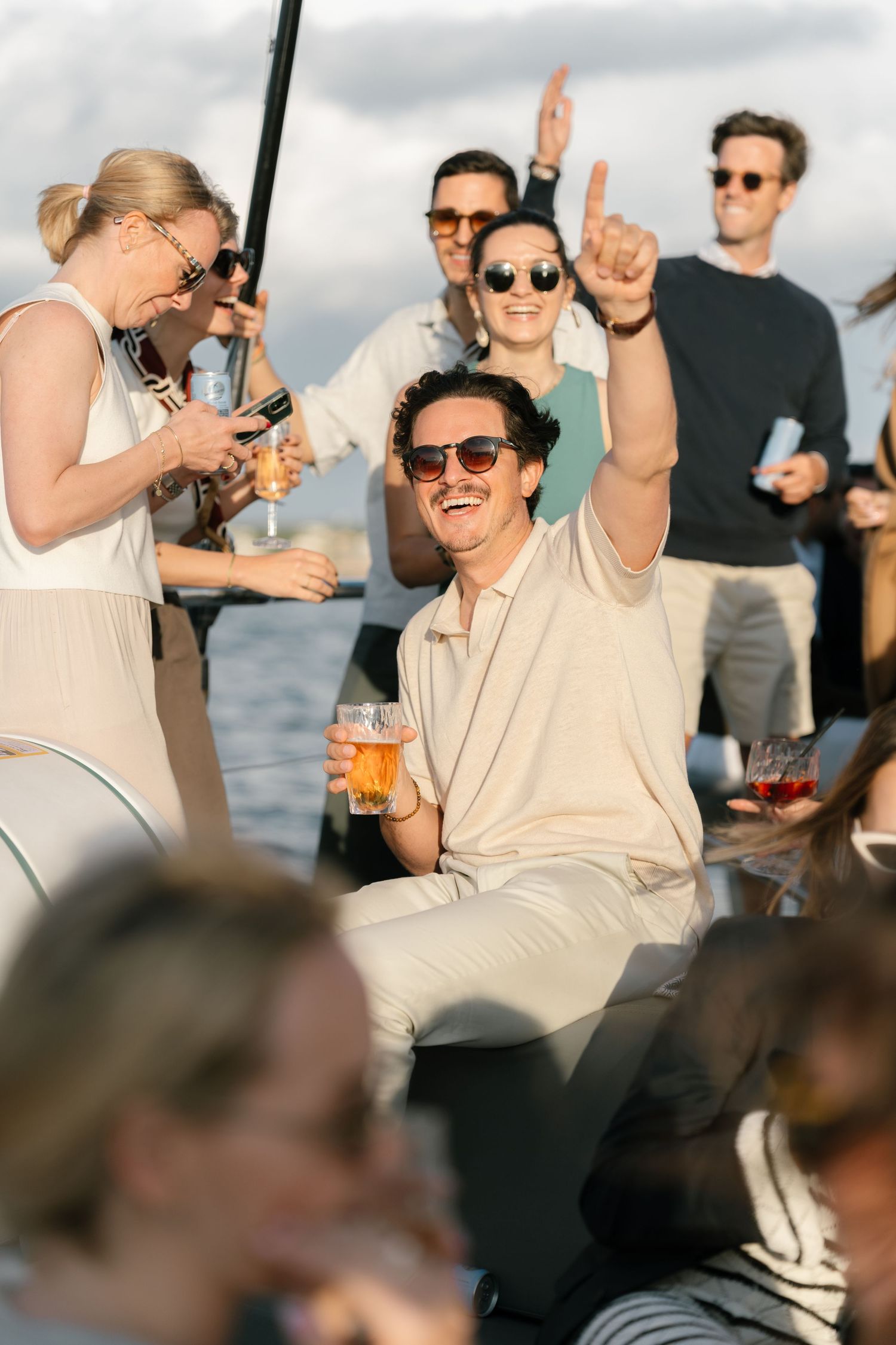 Friends celebrate and raise drinks together during a sunset boat party.