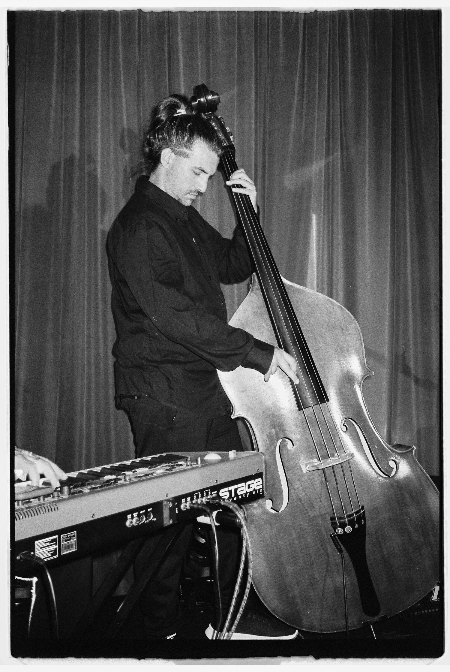 Black and white photos of a musician playing double bass and keyboard at a performance.
