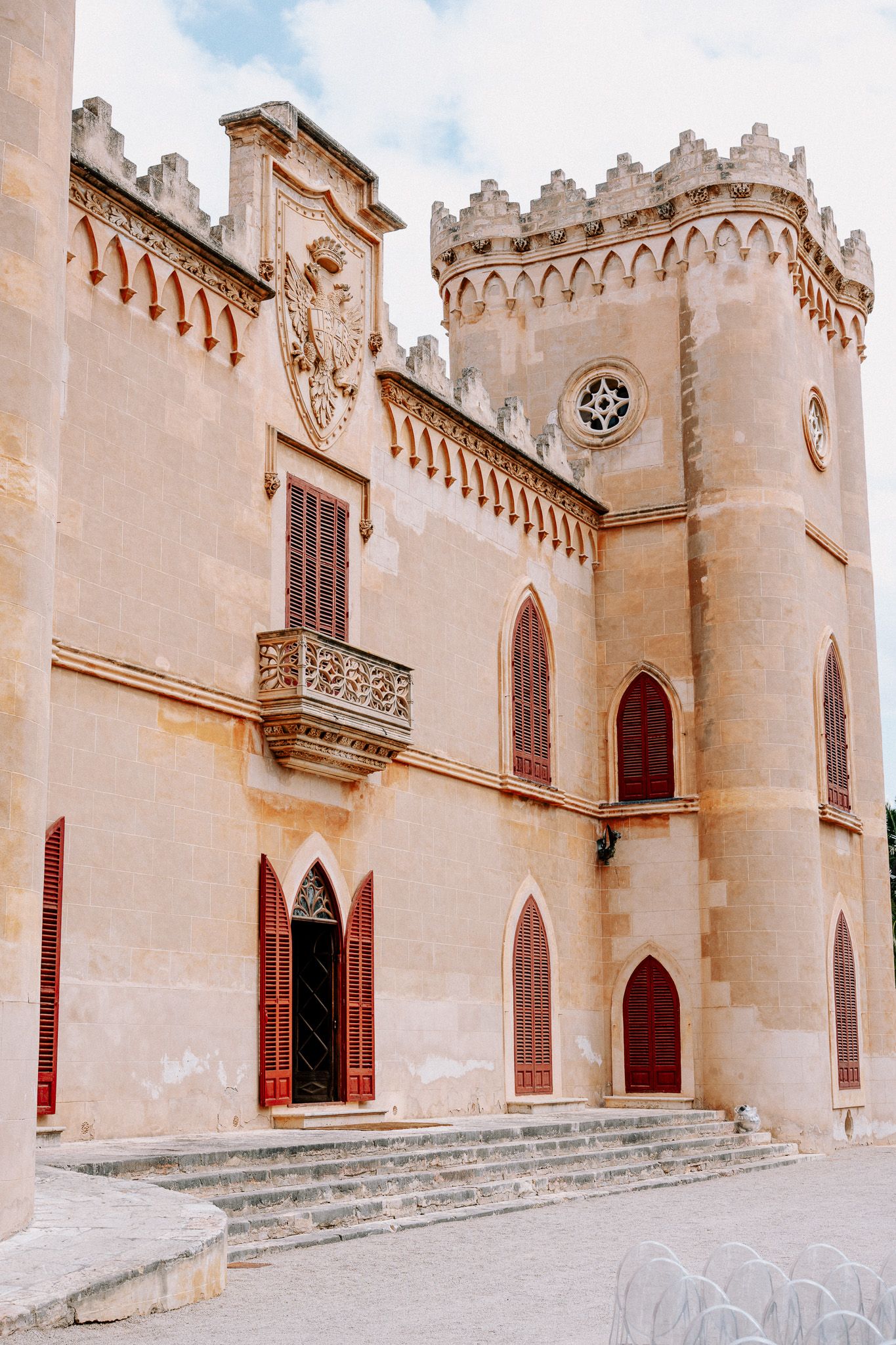Historic Gothic-style castle Castillo de Bendinat with ornate battlements, arched windows, and decorative balcony under a cloudy sky.