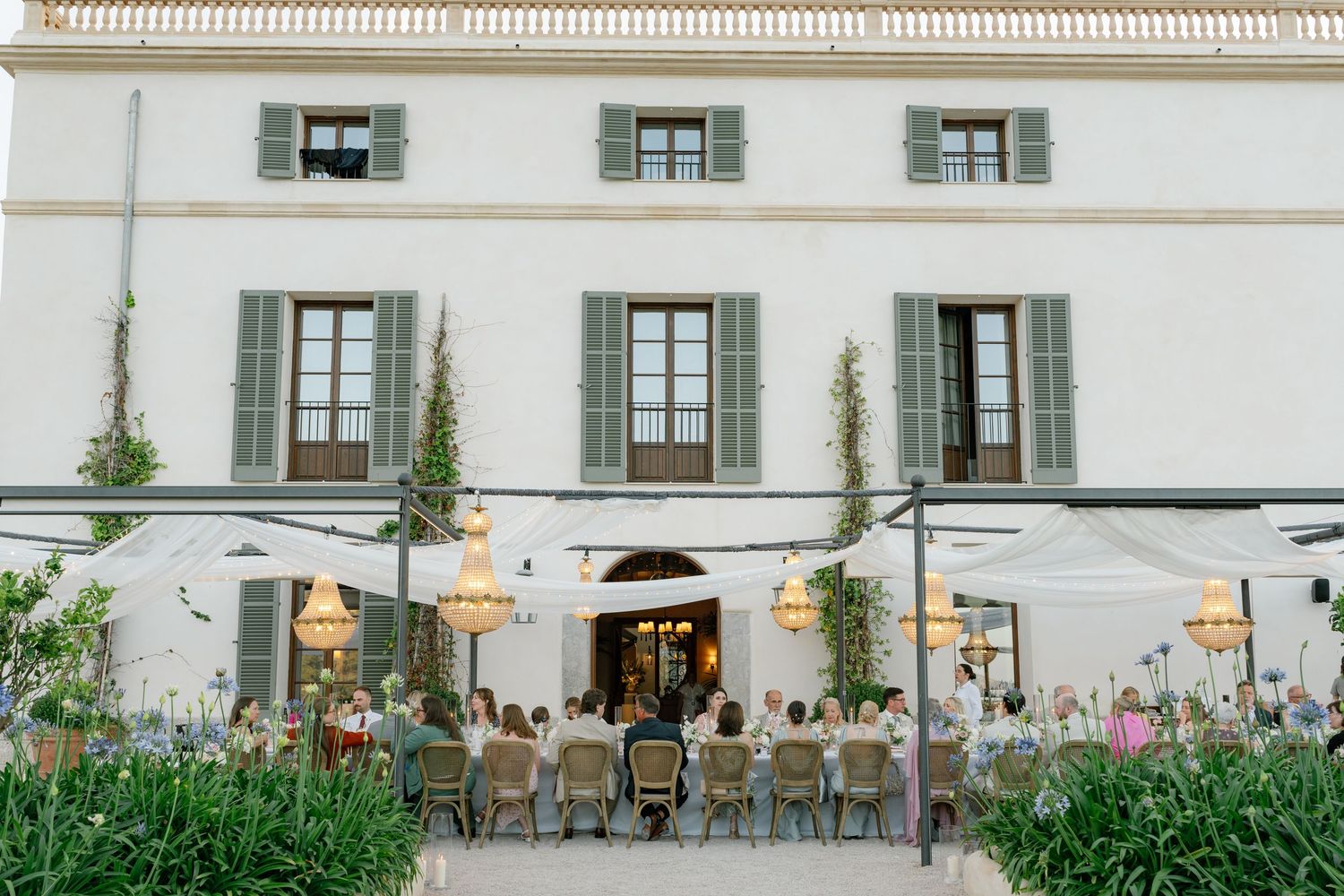 Exterior view of elegant white wedding venue with traditional architecture and landscaping.