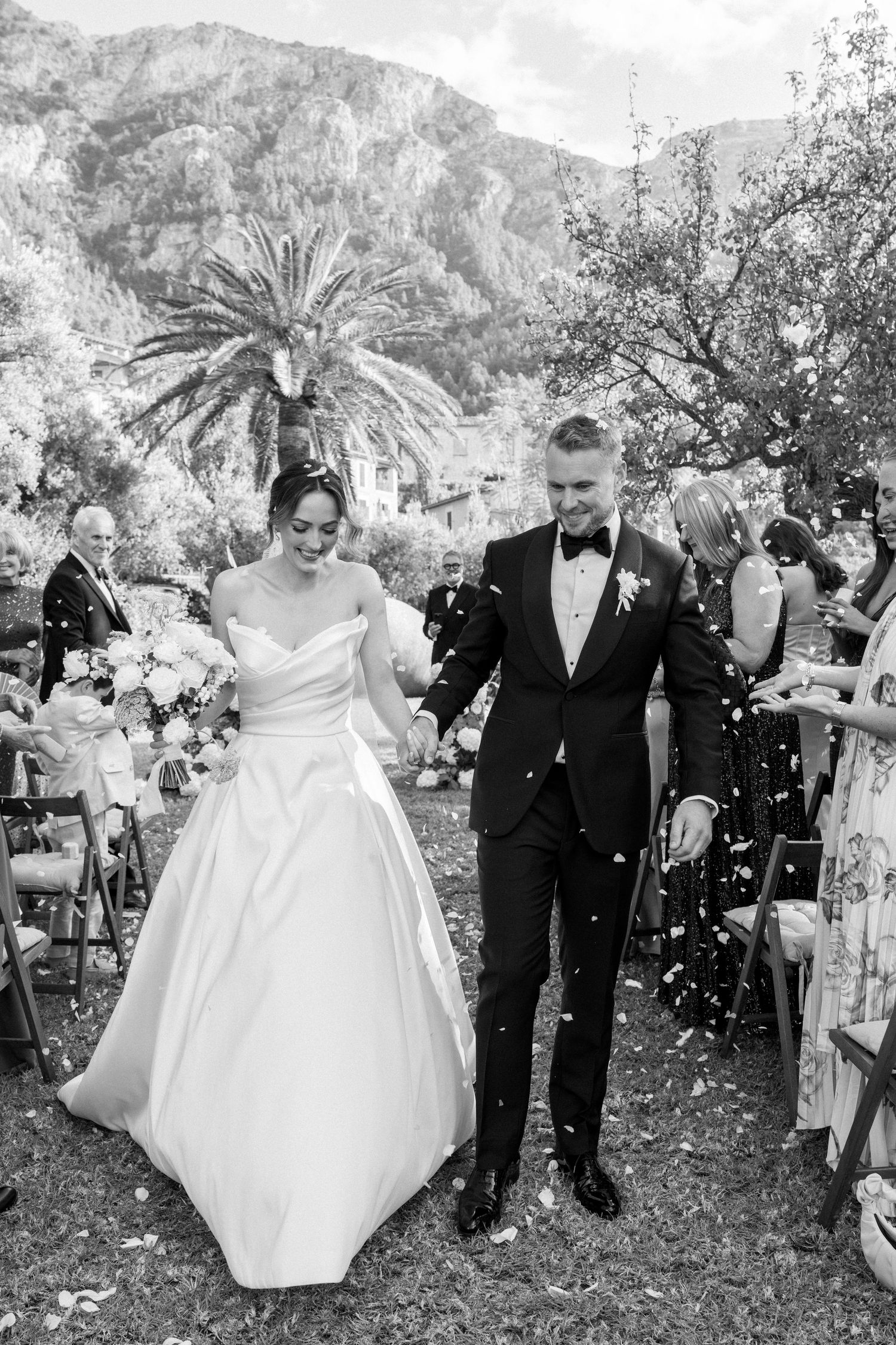 Wedding guests shower the newlyweds with confetti during their outdoor celebration.