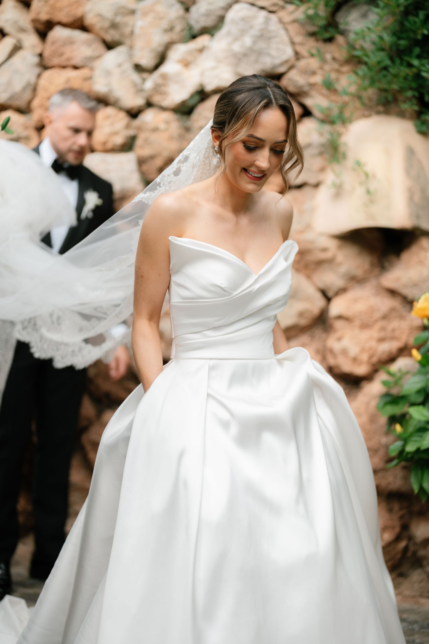 Close-up details of an elegant white wedding dress with pleated fabric and dramatic styling.