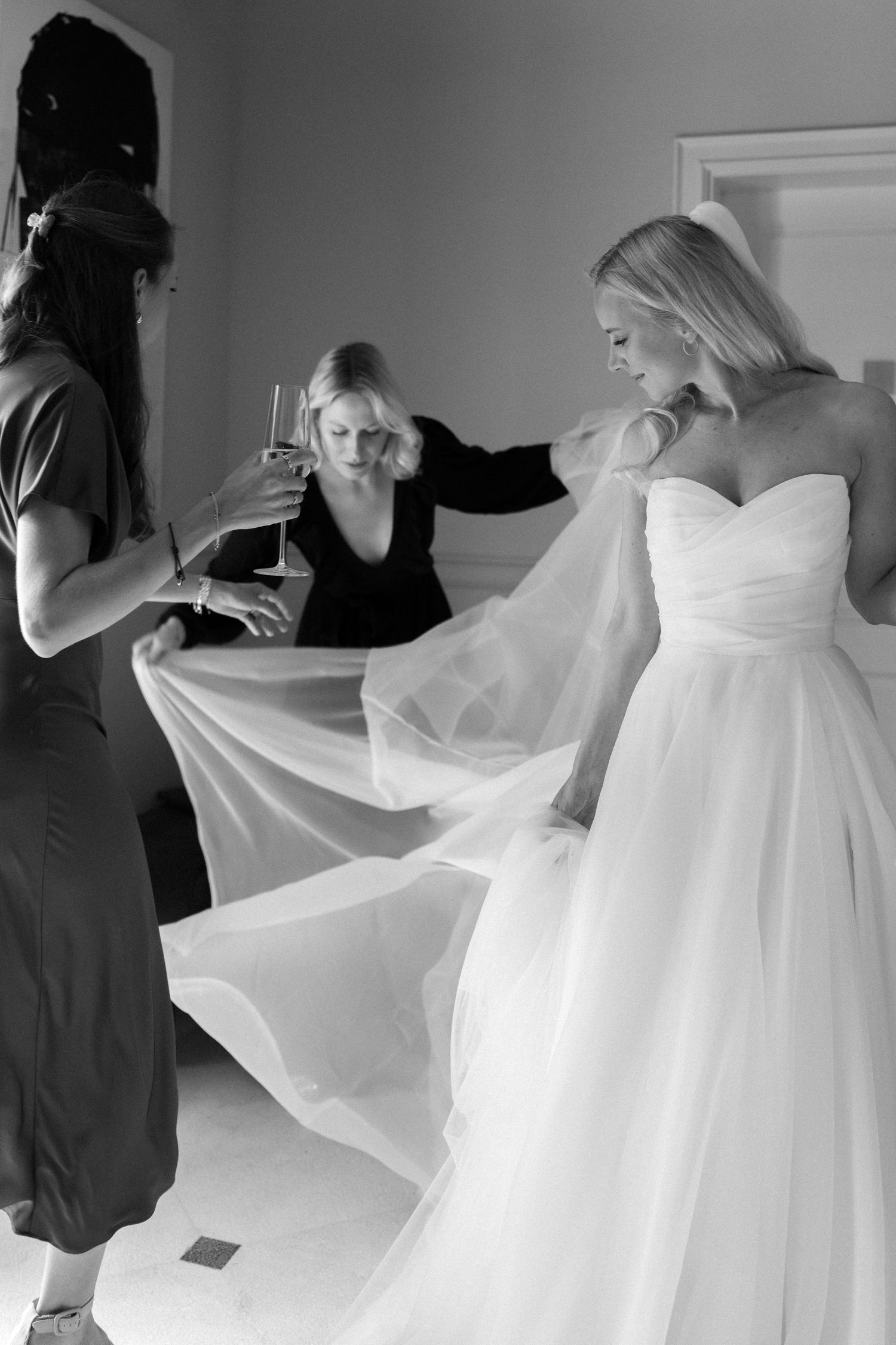 Behind-the-scenes moments of wedding dress preparation in black and white.