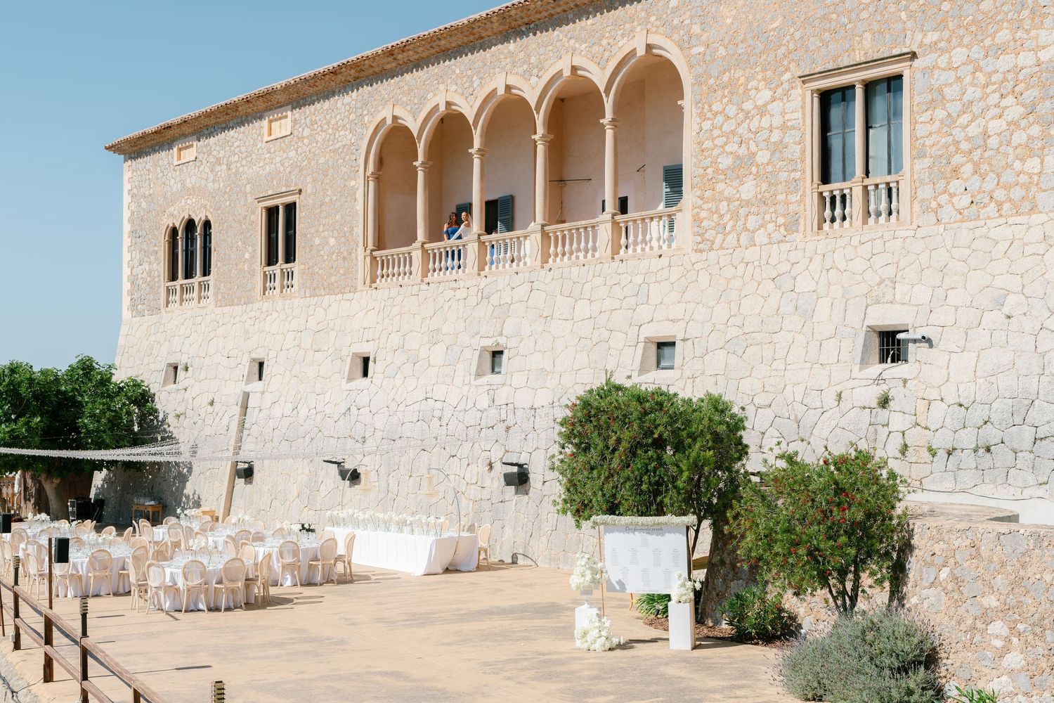 Mediterranean stone villa with arched windows and balconies against a sunny sky.
