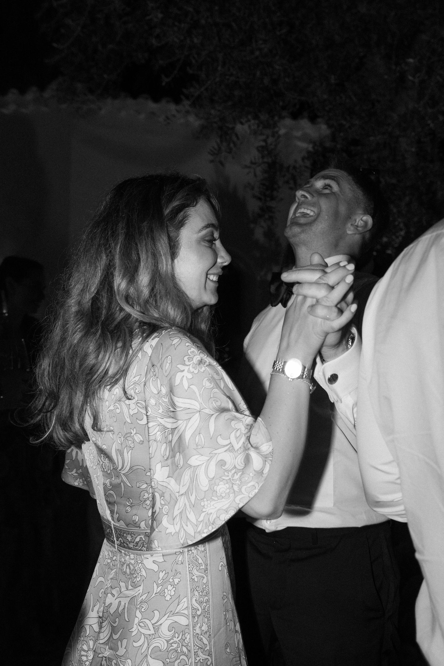 Wedding guests dancing and laughing together at an evening celebration.