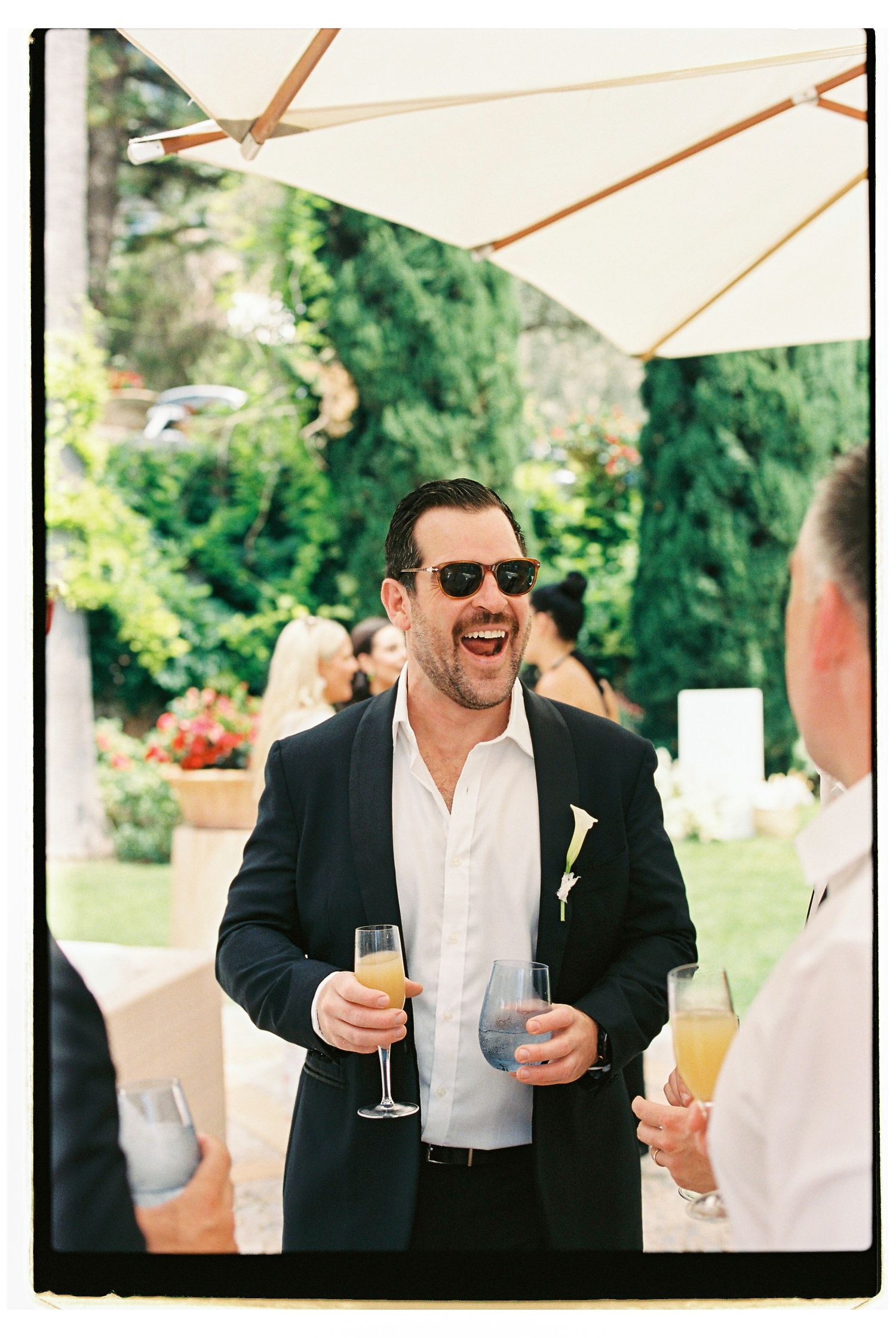 Guest enjoying drinks and conversation under outdoor umbrella.