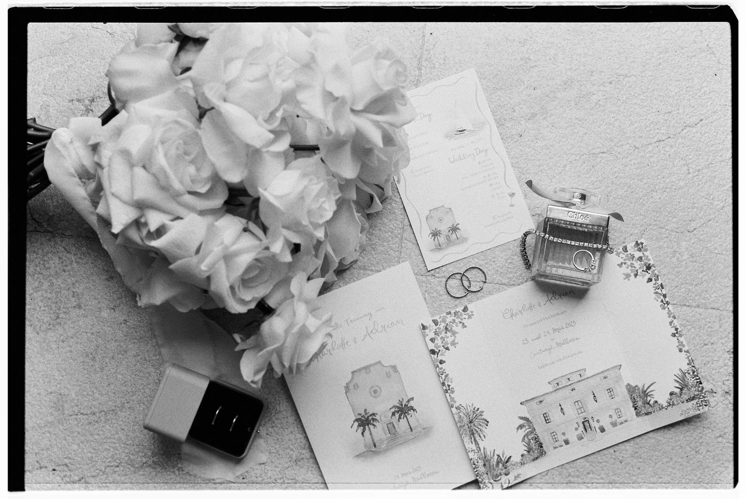 Wedding details including flowers and invitation cards arranged in black and white.