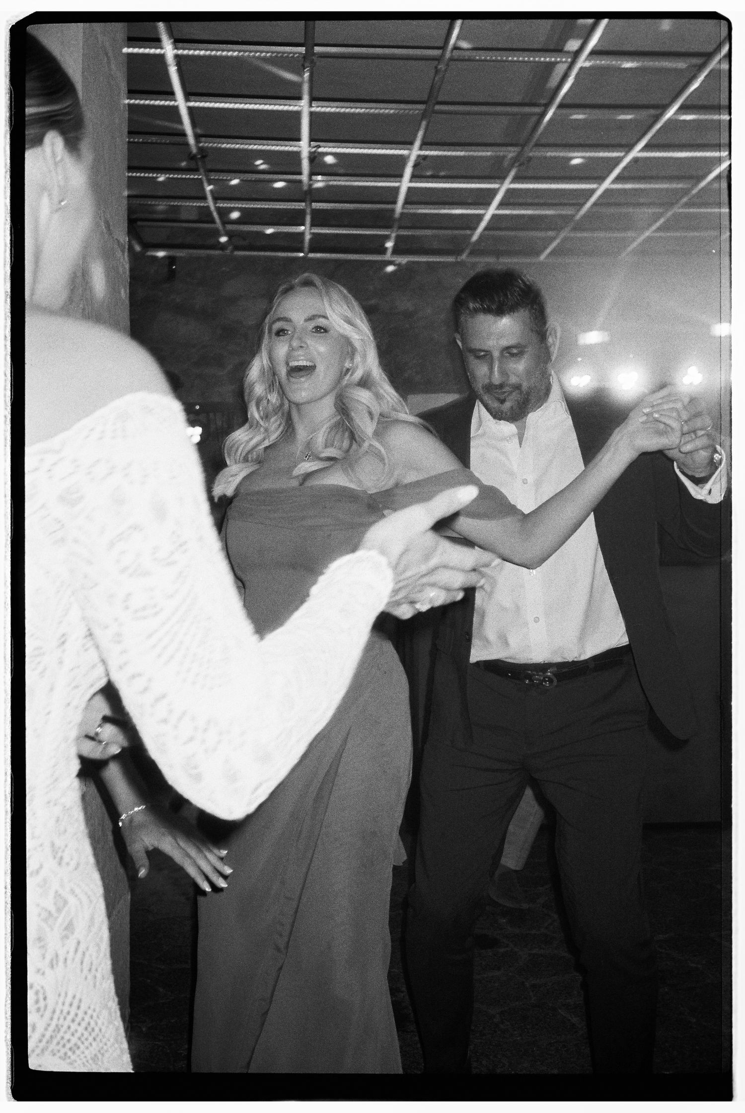 People dancing energetically at a nighttime celebration in formal attire.
