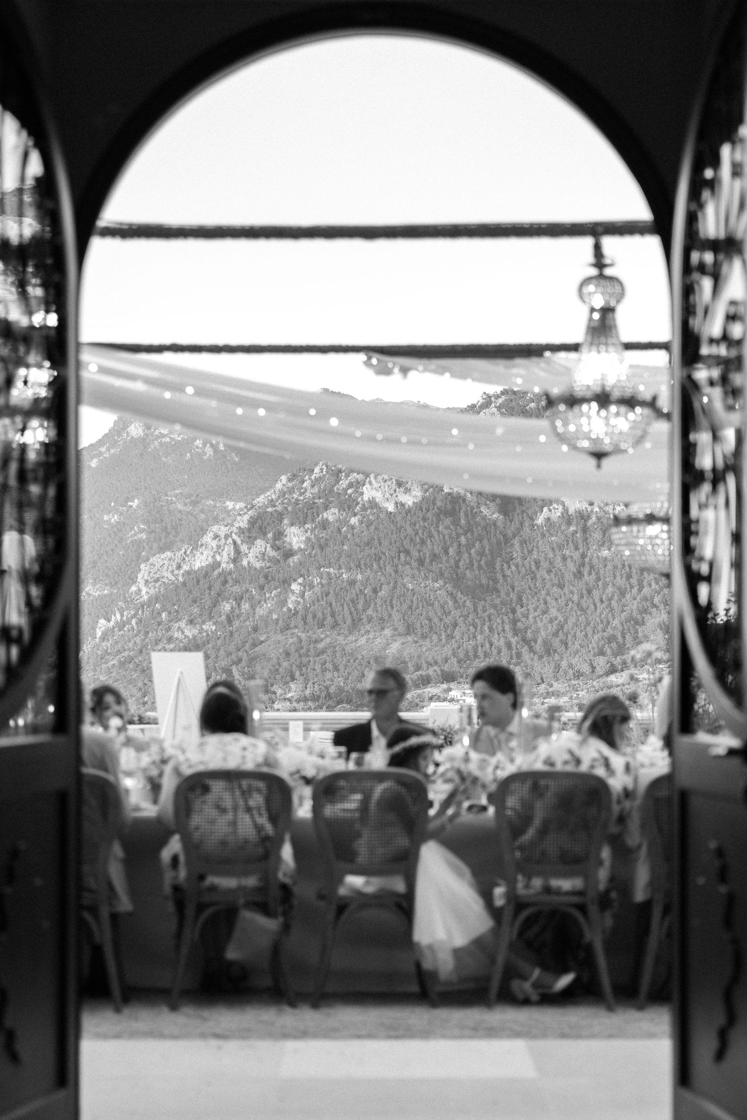 Wedding venue interior with arched windows overlooking mountain landscape.