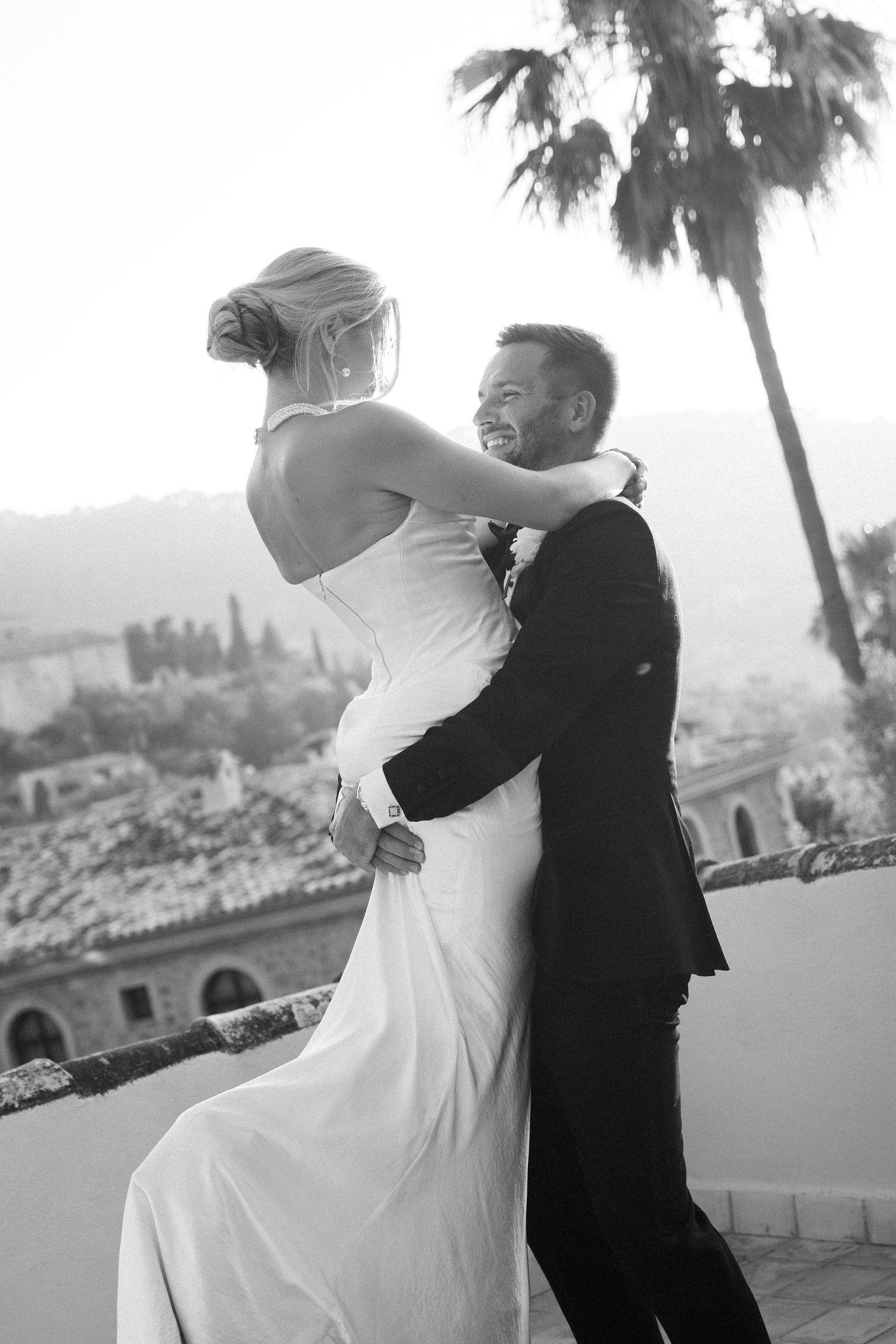 Black and white romantic wedding photos showing couple embracing on a scenic terrace.