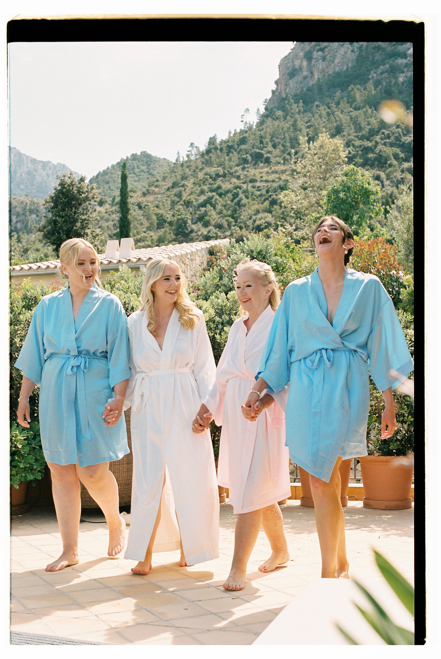 Four matching light blue and white robes hanging on a sunny outdoor patio with mountain views.