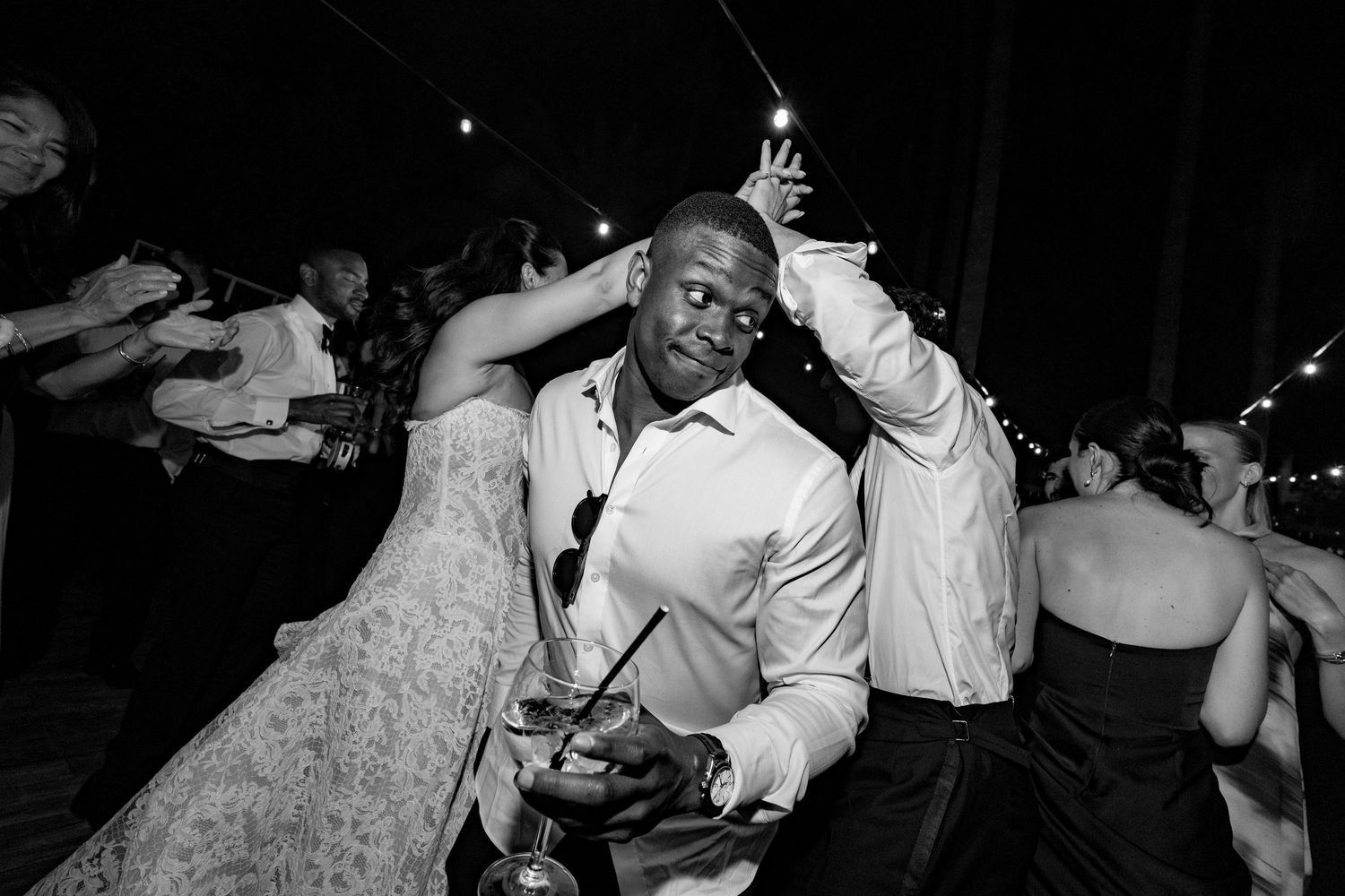 Man dancing energetically at a wedding reception in black and white photography.