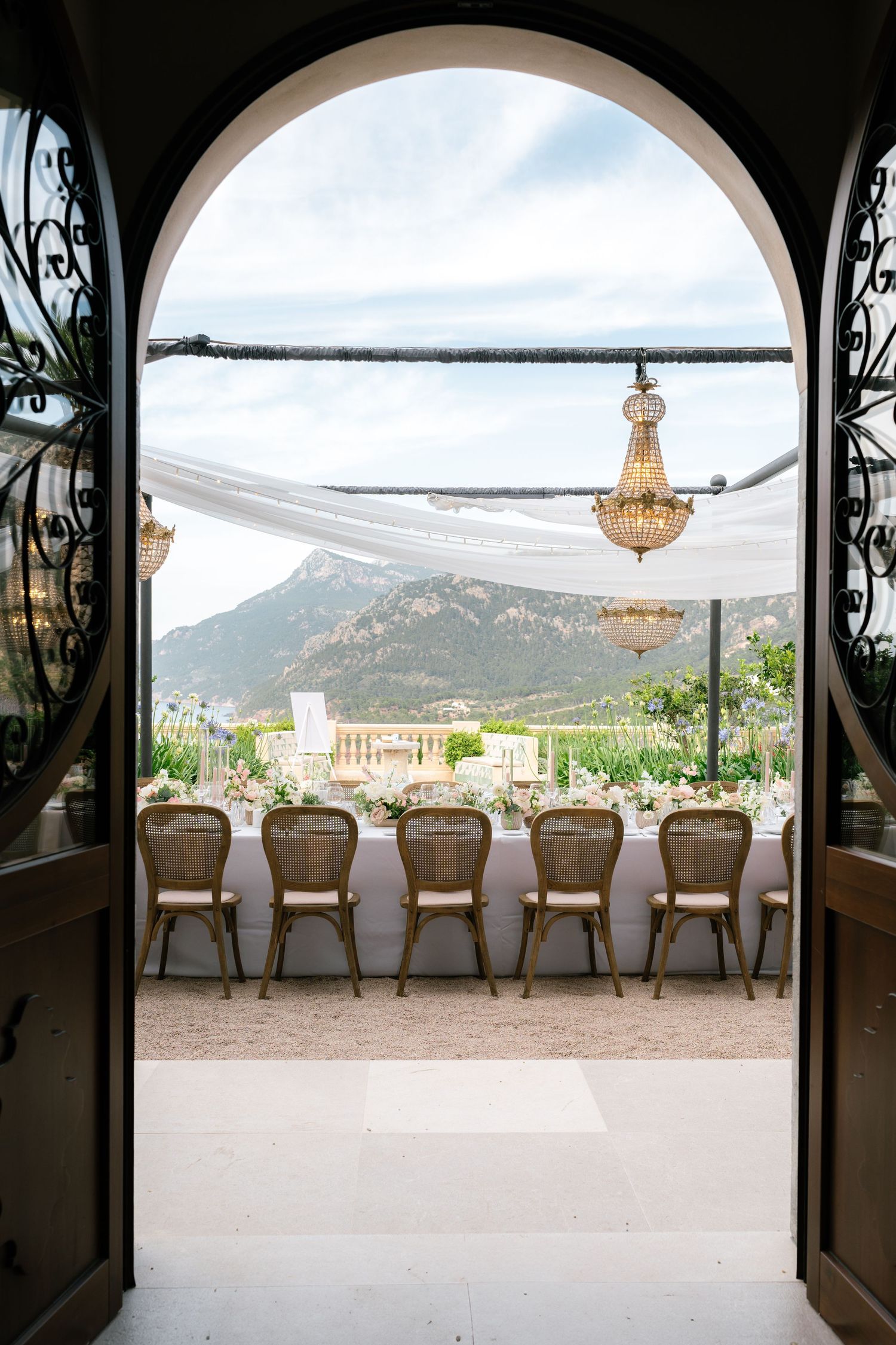 Elegant wedding venue with arched doorways framing mountain views and crystal chandeliers.