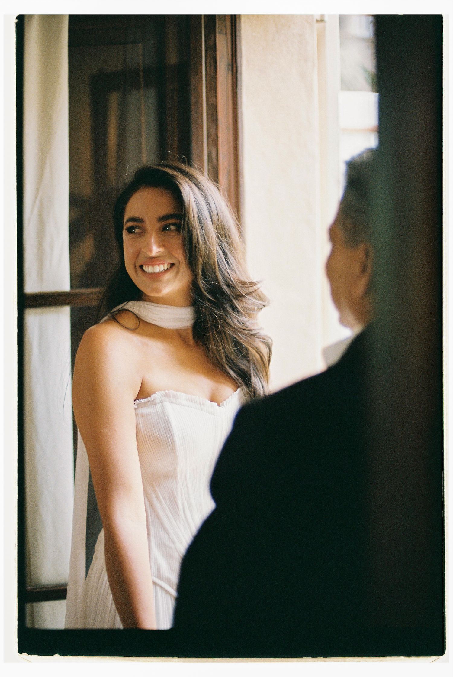 Soft-lit portrait in white dress against window light.