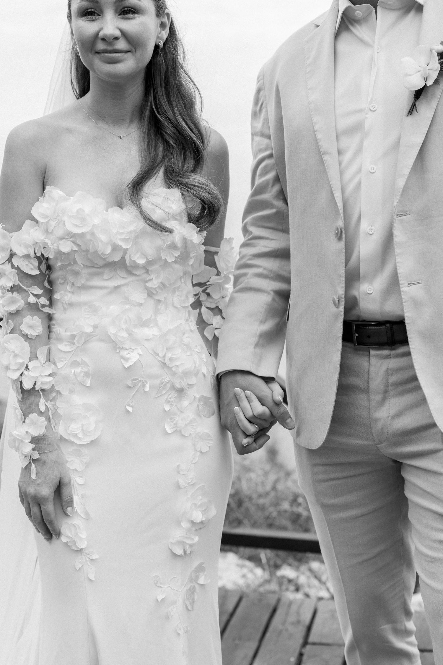 Detail shots of a wedding dress with floral appliques and light-colored suit.
