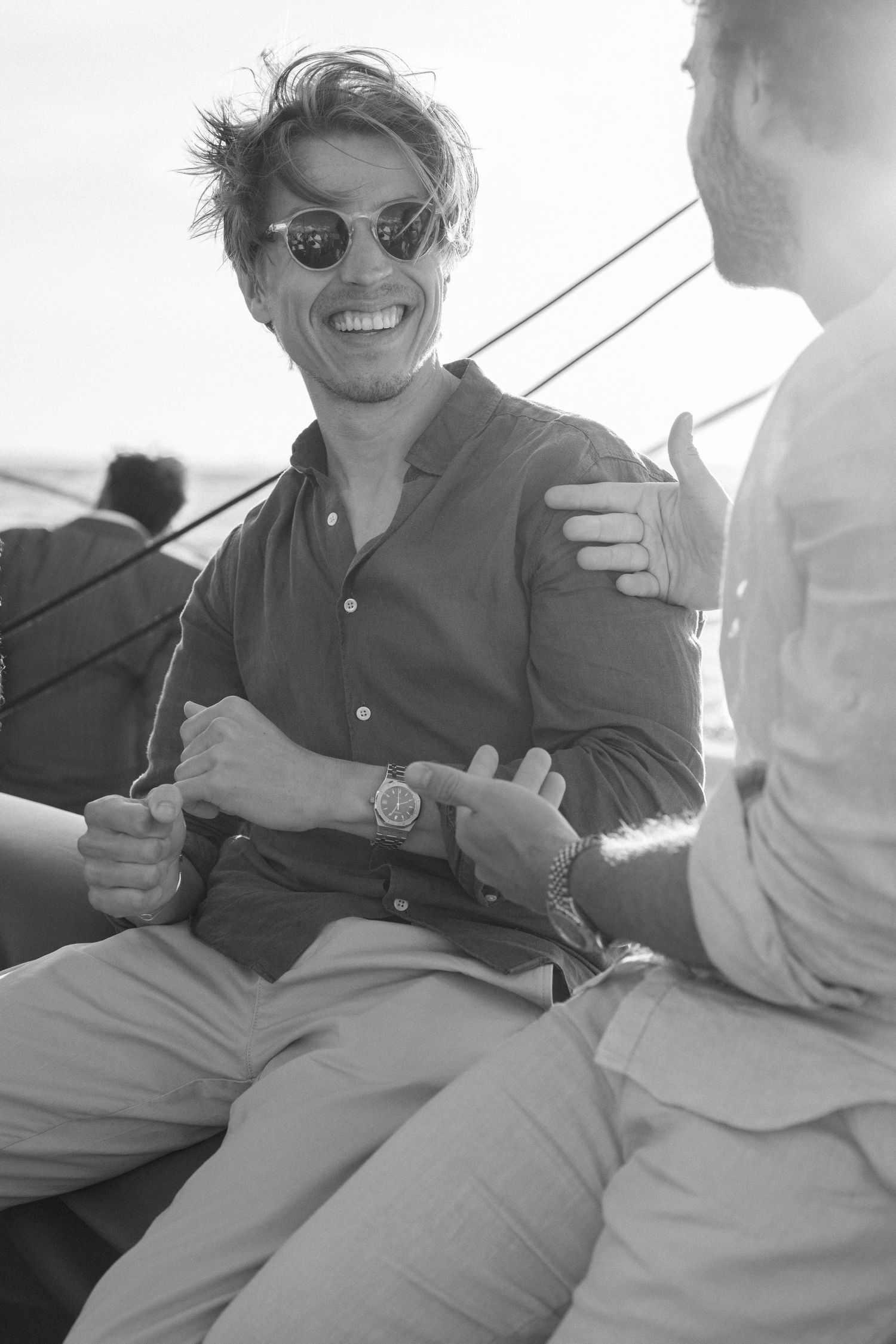 Casual conversation between passengers relaxing on a boat deck in the sunlight.