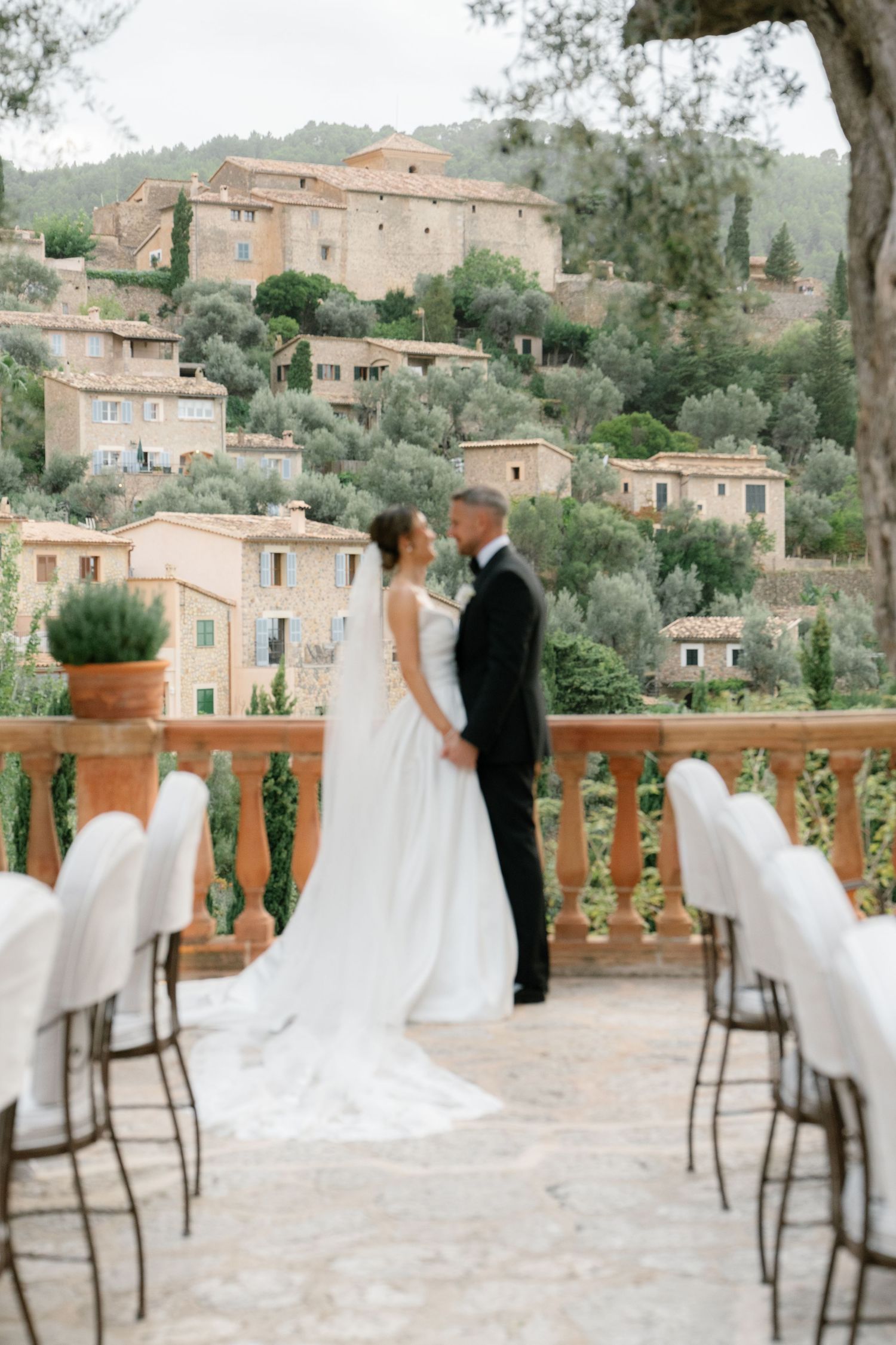 Wedding reception setup on a stone terrace with mountain views and elegant chairs.