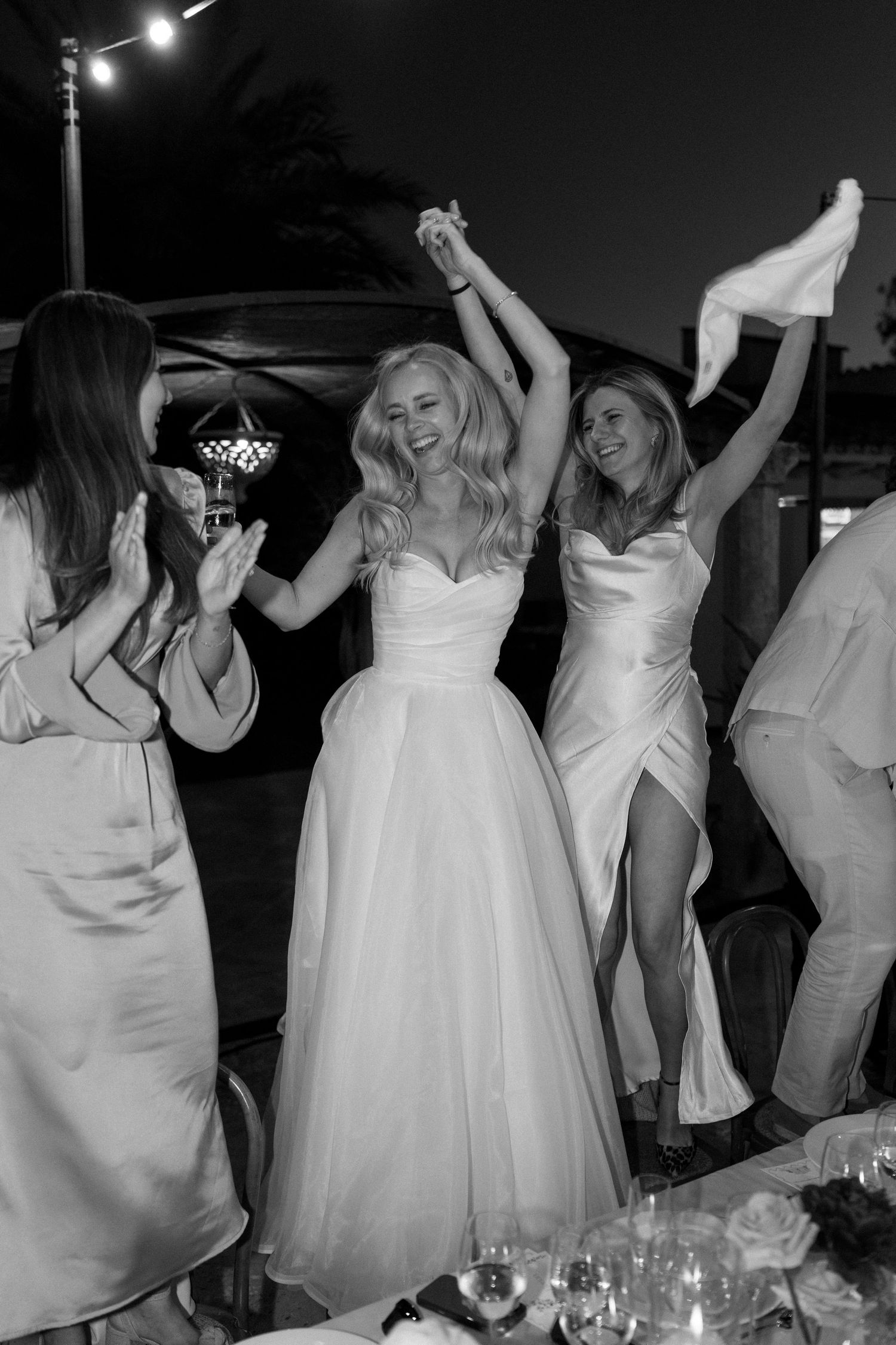 Wedding party dances and celebrates during nighttime outdoor reception.