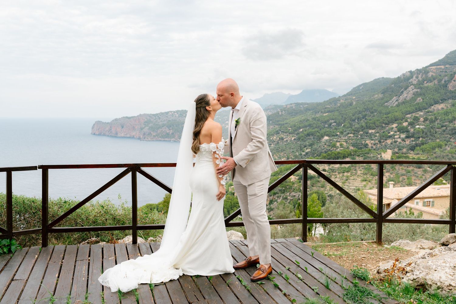 Wedding couple shares romantic moments on a mountaintop terrace with stunning coastal views.