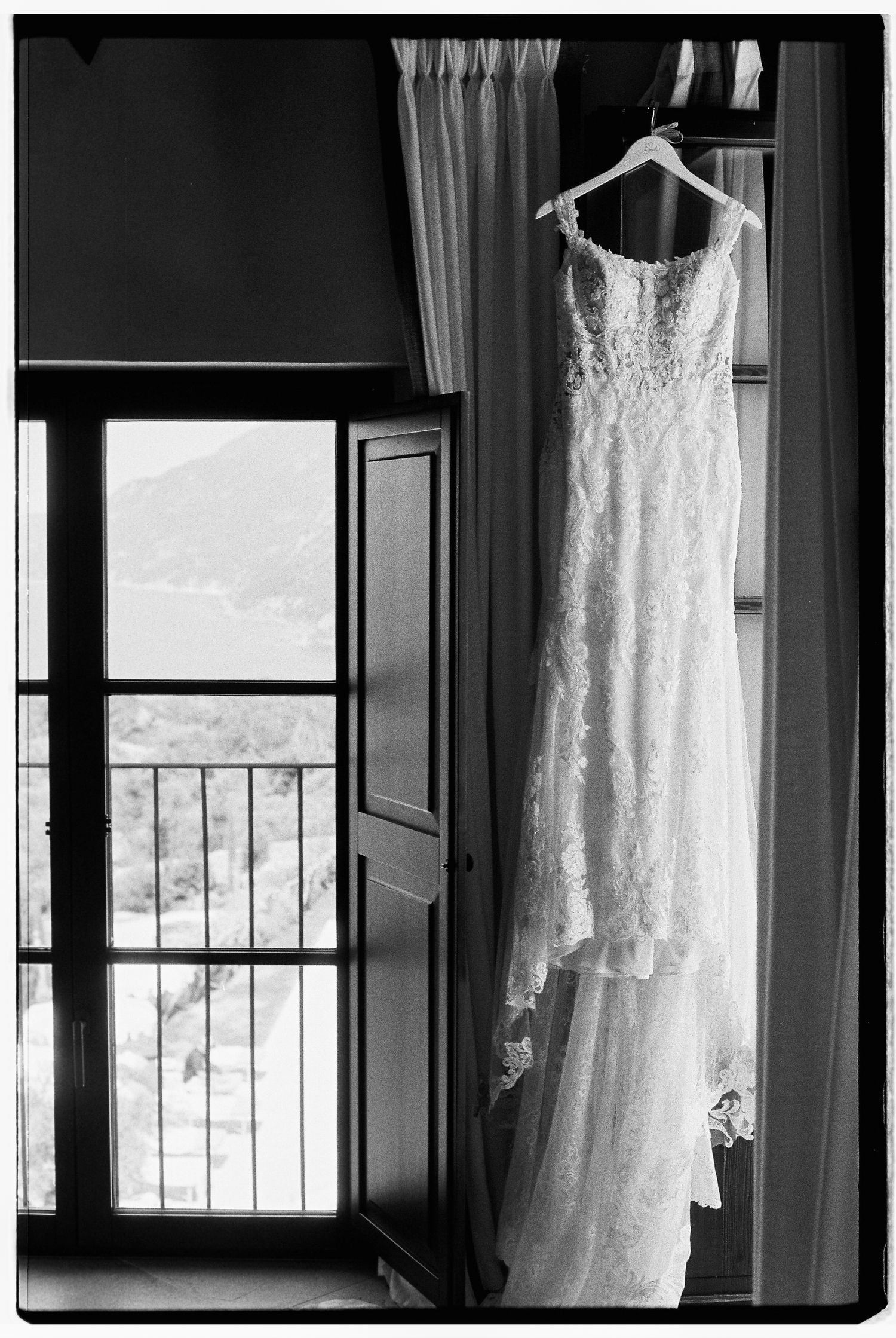 Wedding dress hanging in window frame with mountain vista visible in background.