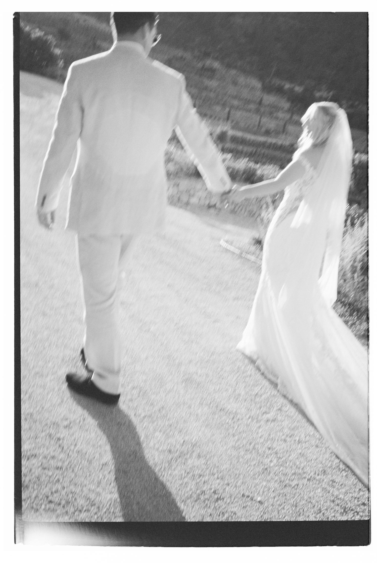 Ethereal black and white photo of wedding party walking outdoors.