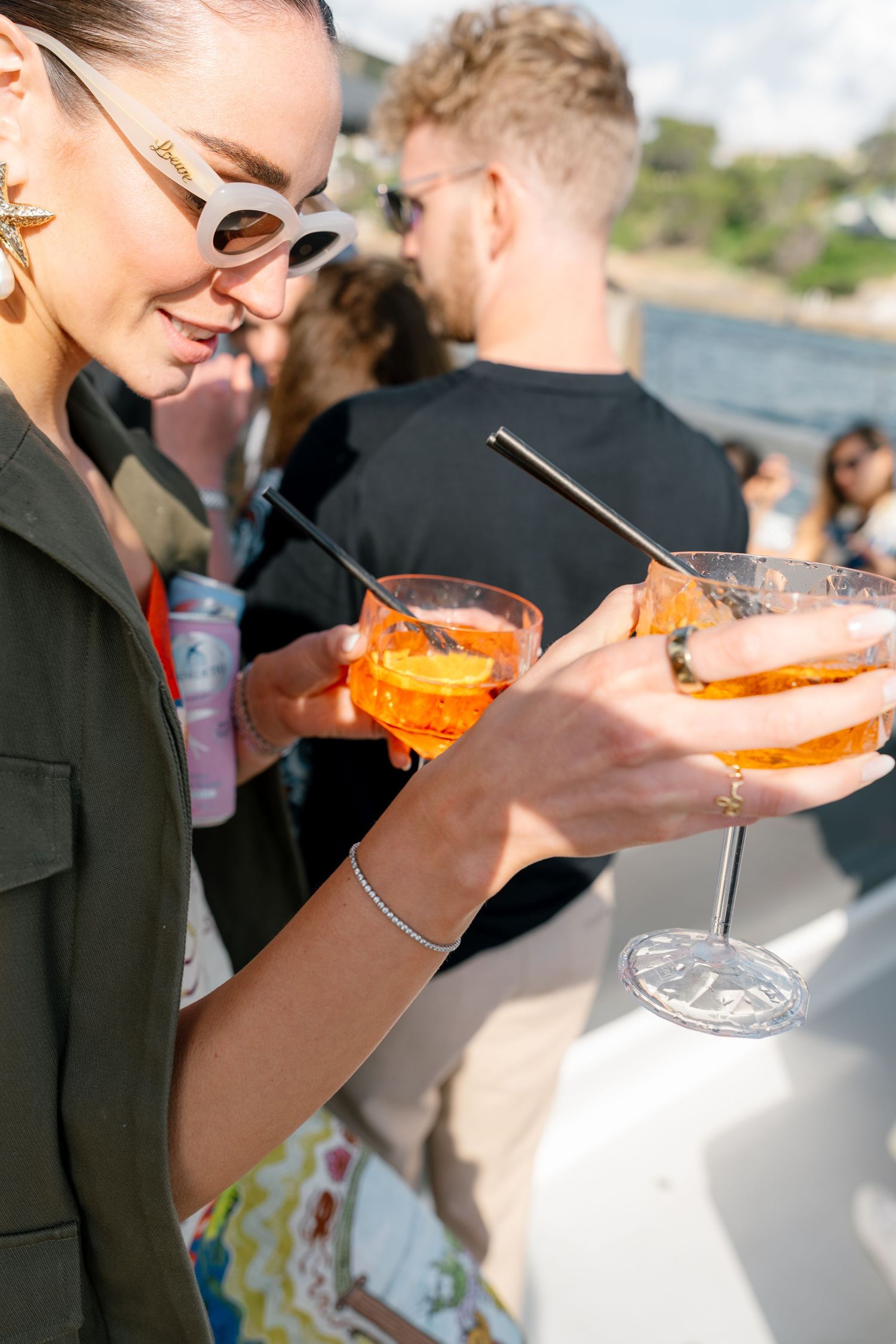 Wedding guests enjoying vibrant orange cocktails served in elegant glassware at an outdoor reception.