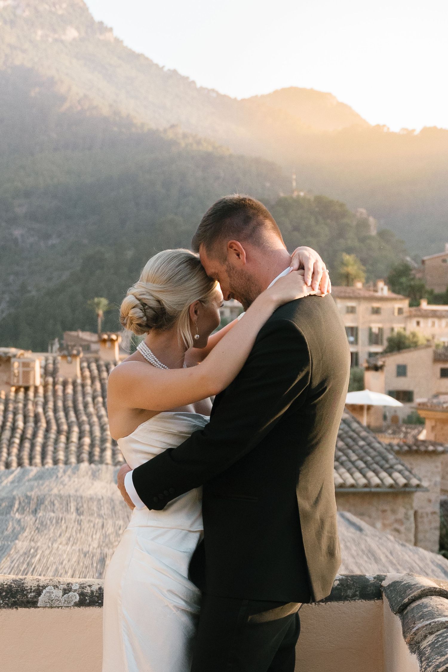 Intimate wedding moment shared during golden hour with Mediterranean architecture in background.