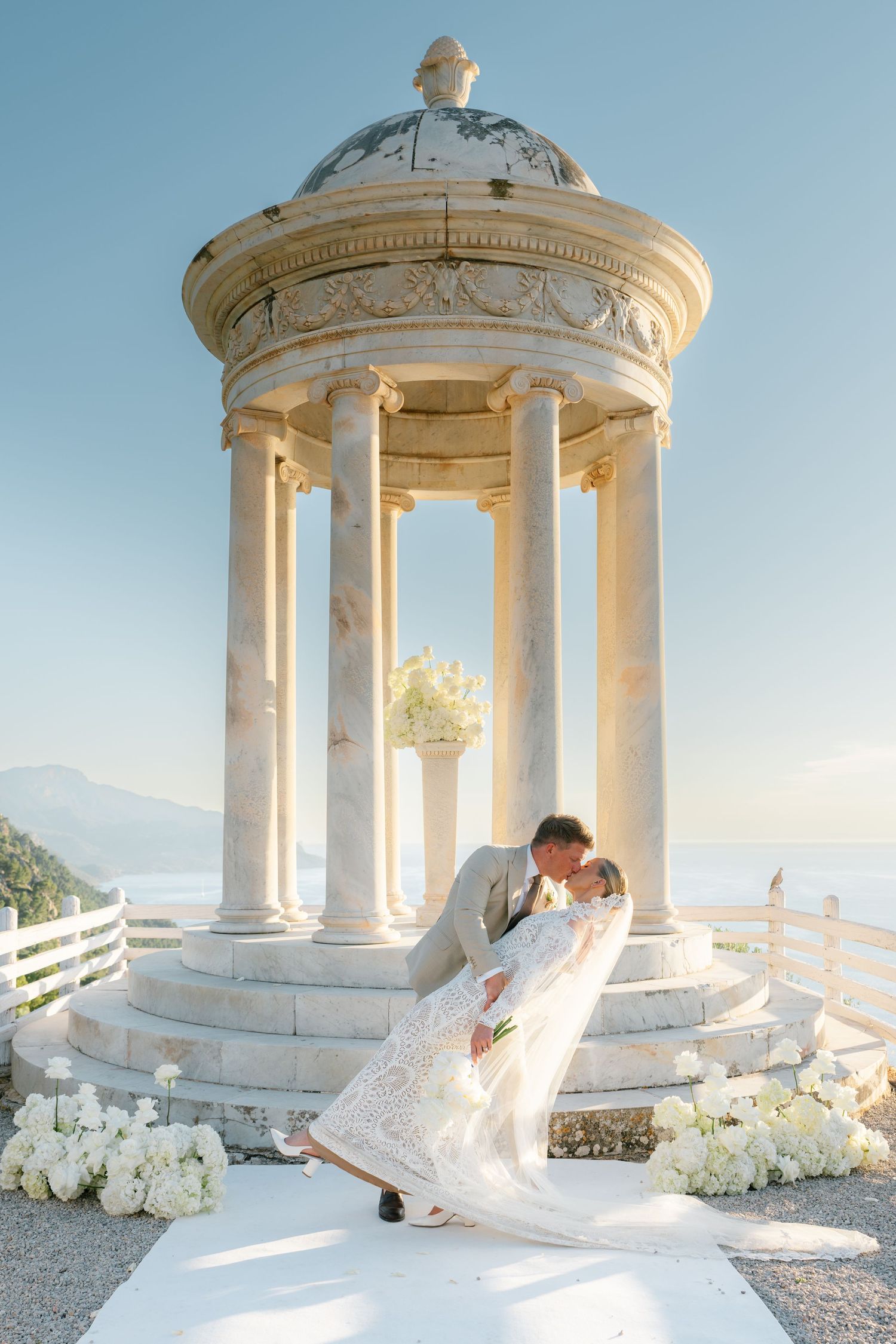 Romantic wedding photos taken at a white stone gazebo with mountain views.