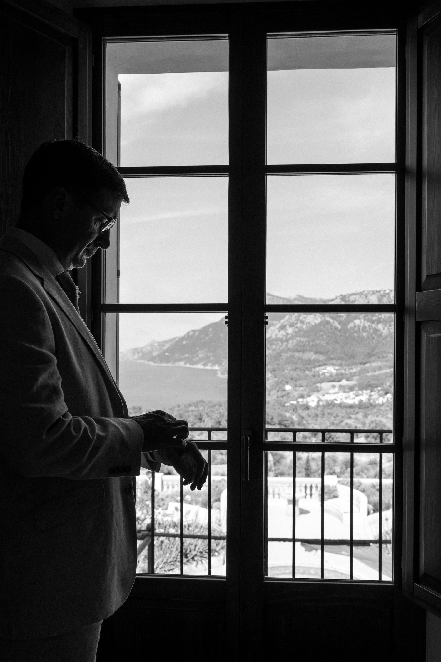 Silhouette by window overlooking Mediterranean coastal landscape.